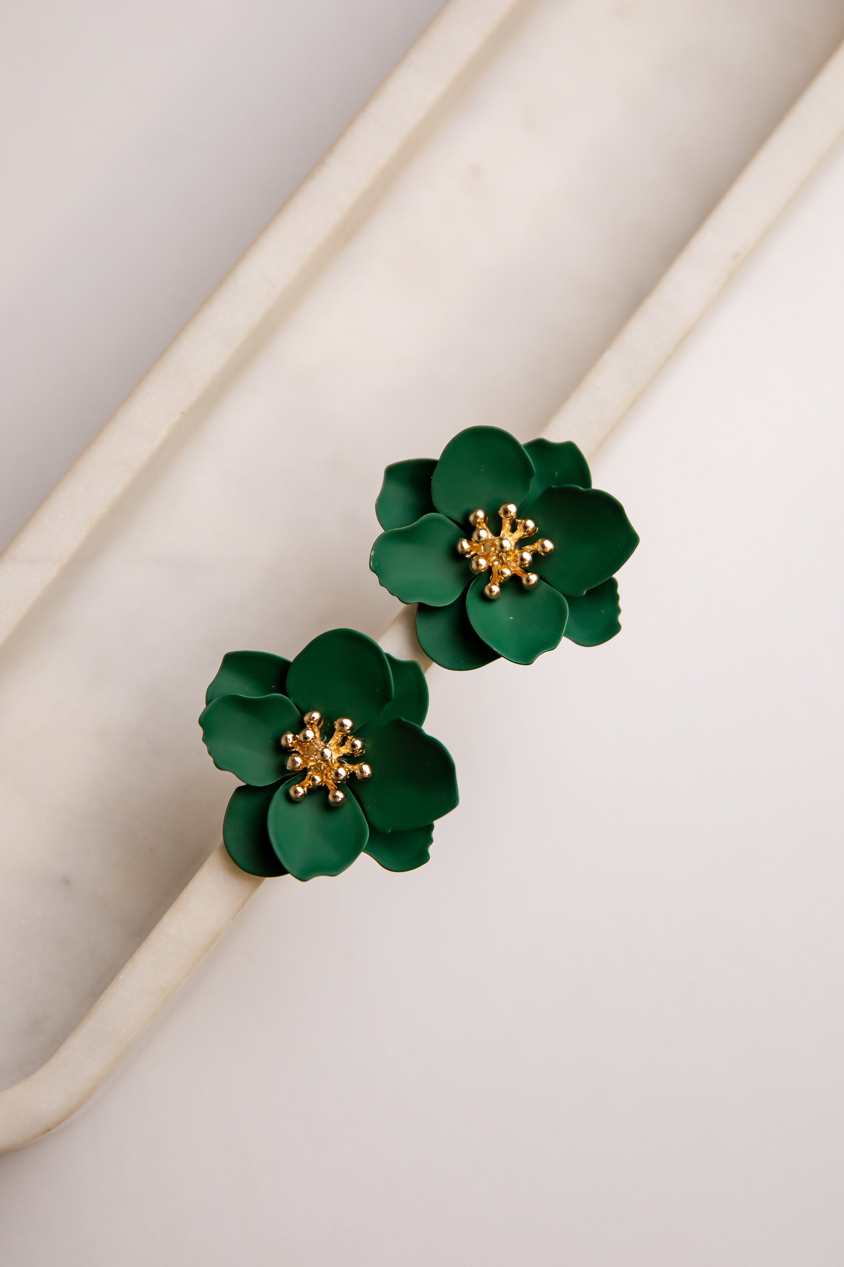 Green floral earrings with gold centers on a light background