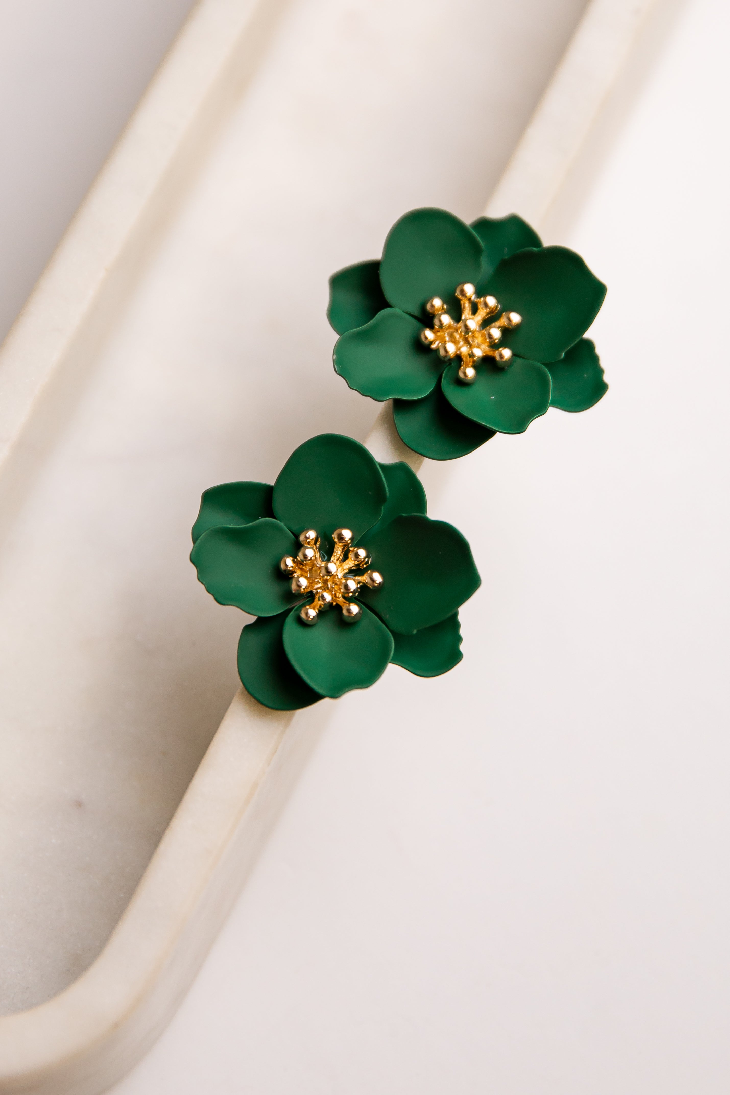 Green floral earrings with gold centers on a white background