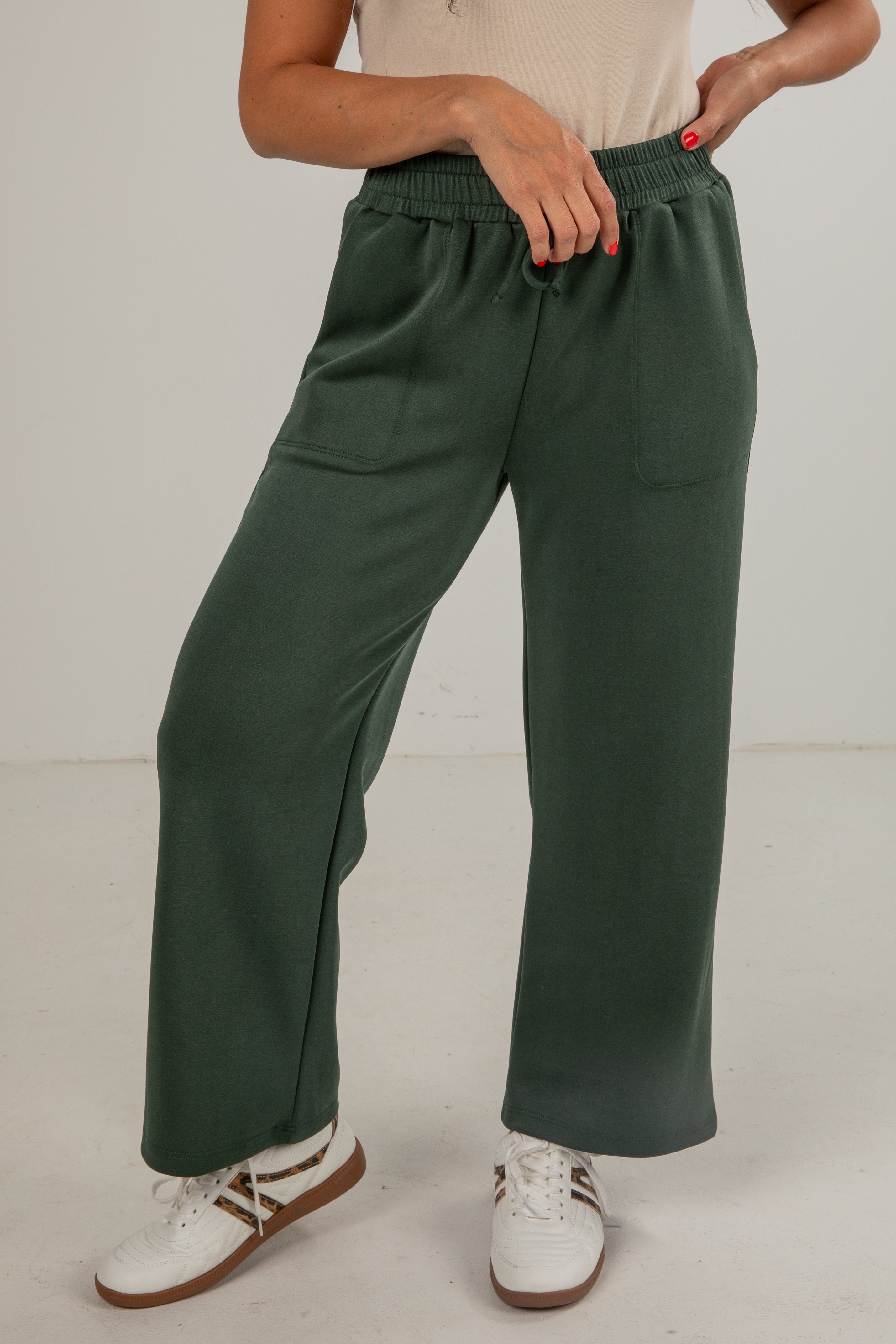 Person wearing green wide-leg pants with a plain background