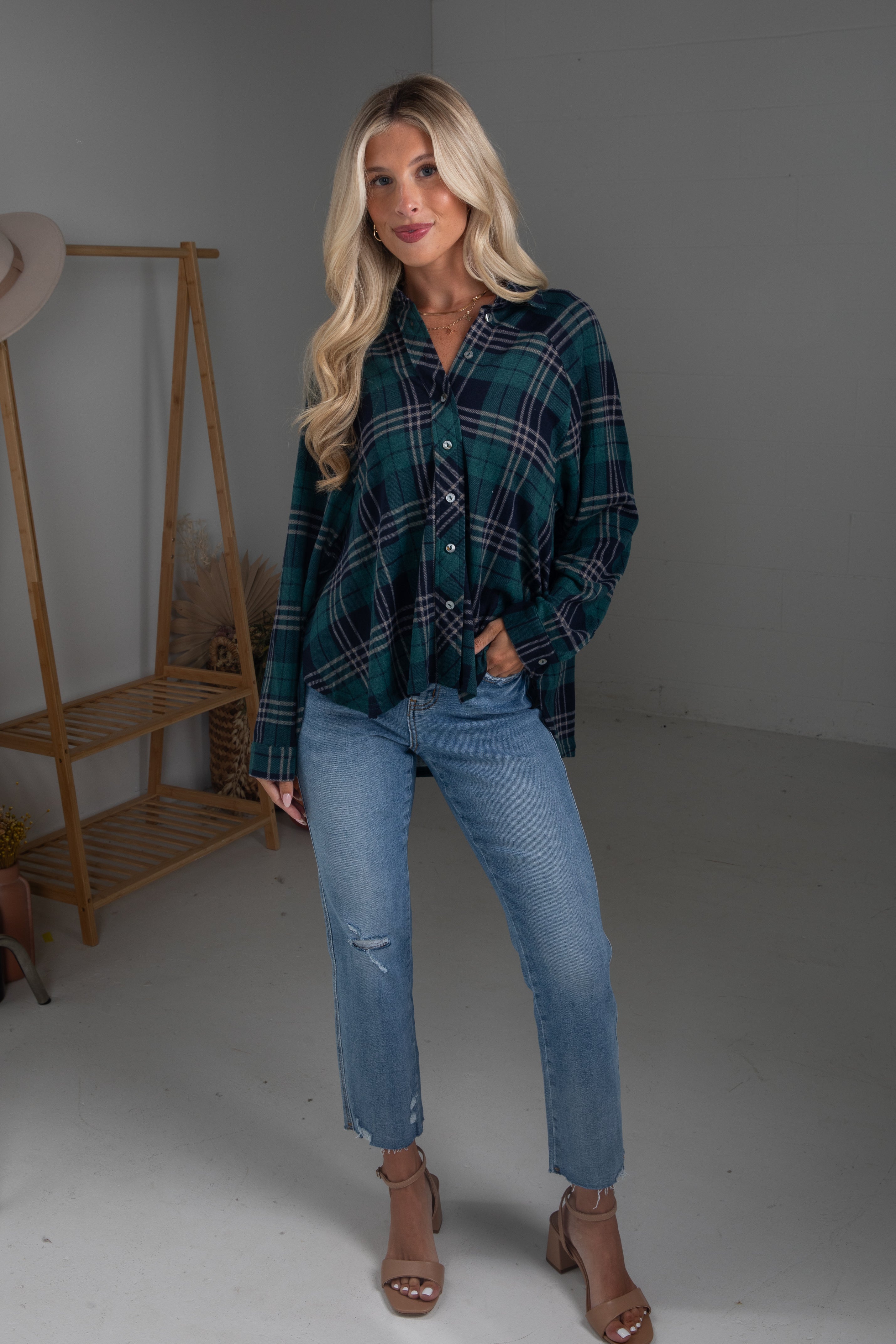 Woman wearing a plaid shirt and jeans standing in a minimalistic room.