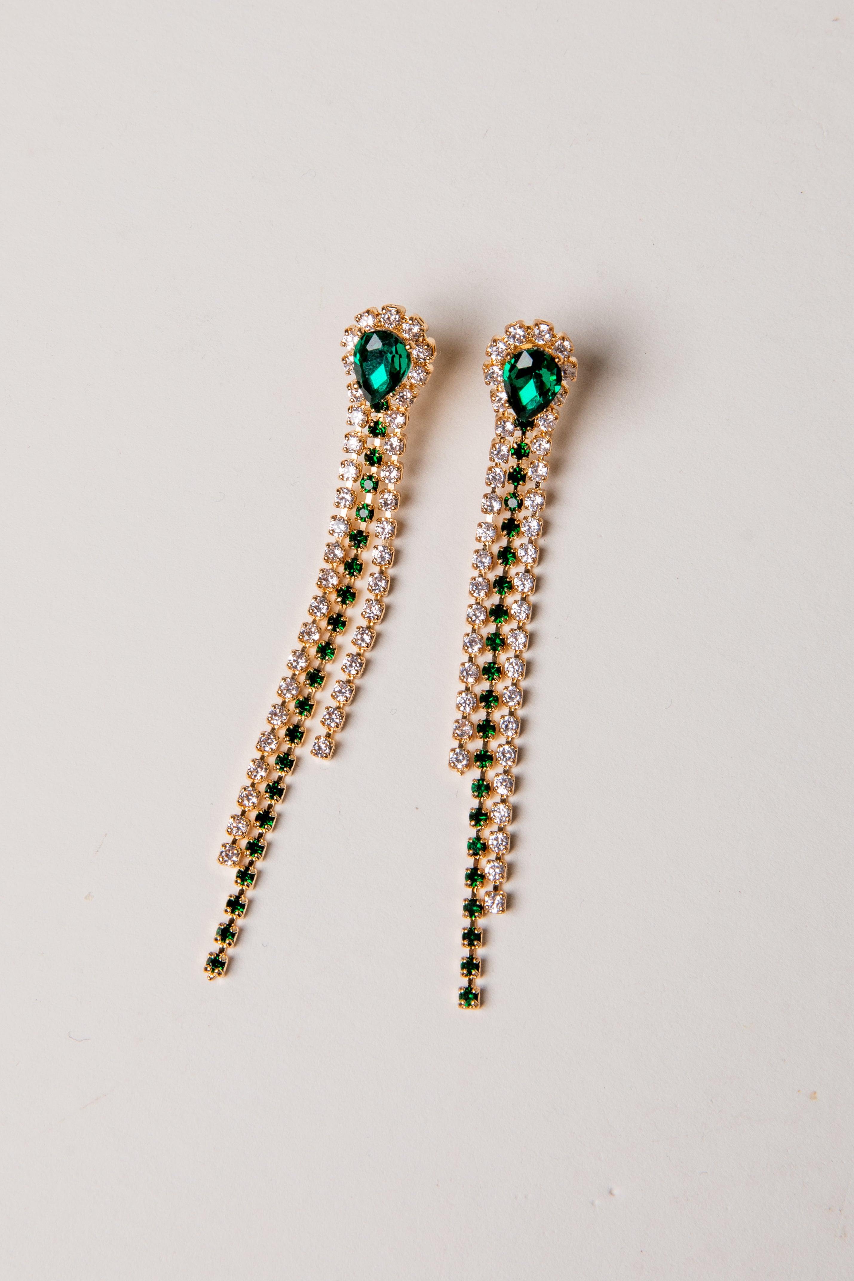 Pair of earrings with green gemstones on a light gray background
