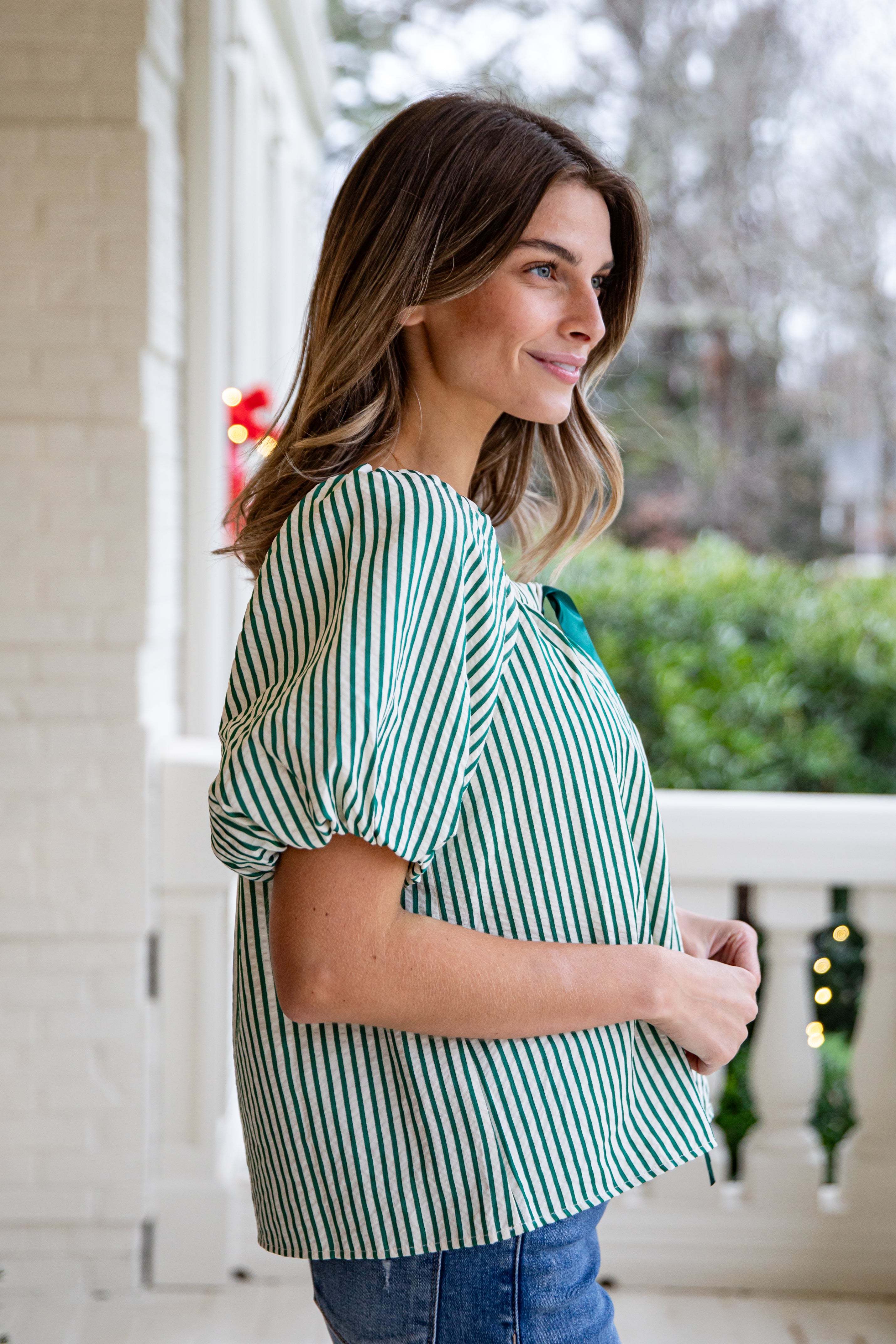 Woman wearing a green and white striped shirt on a porch