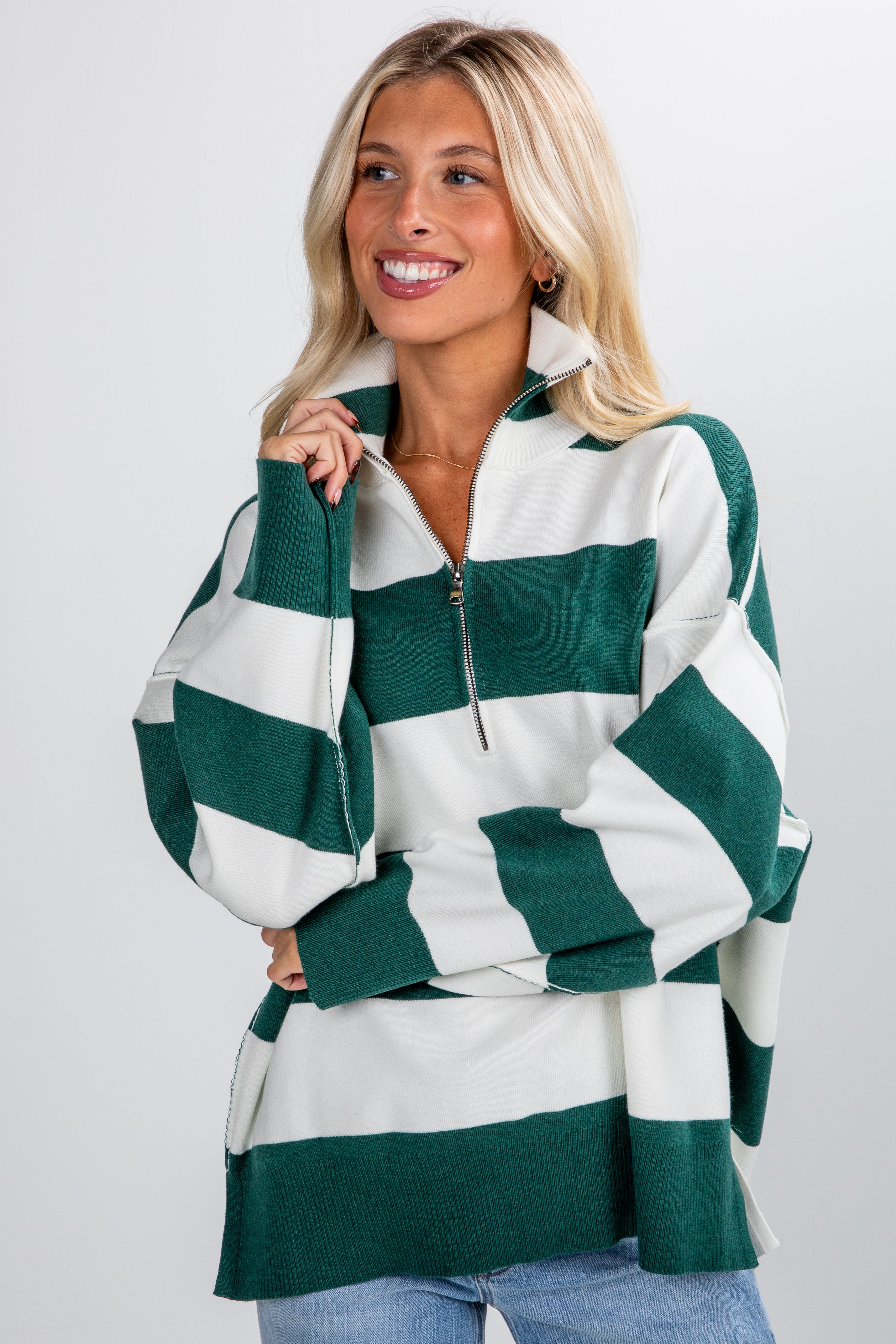 Woman wearing a green and white striped sweater against a plain background