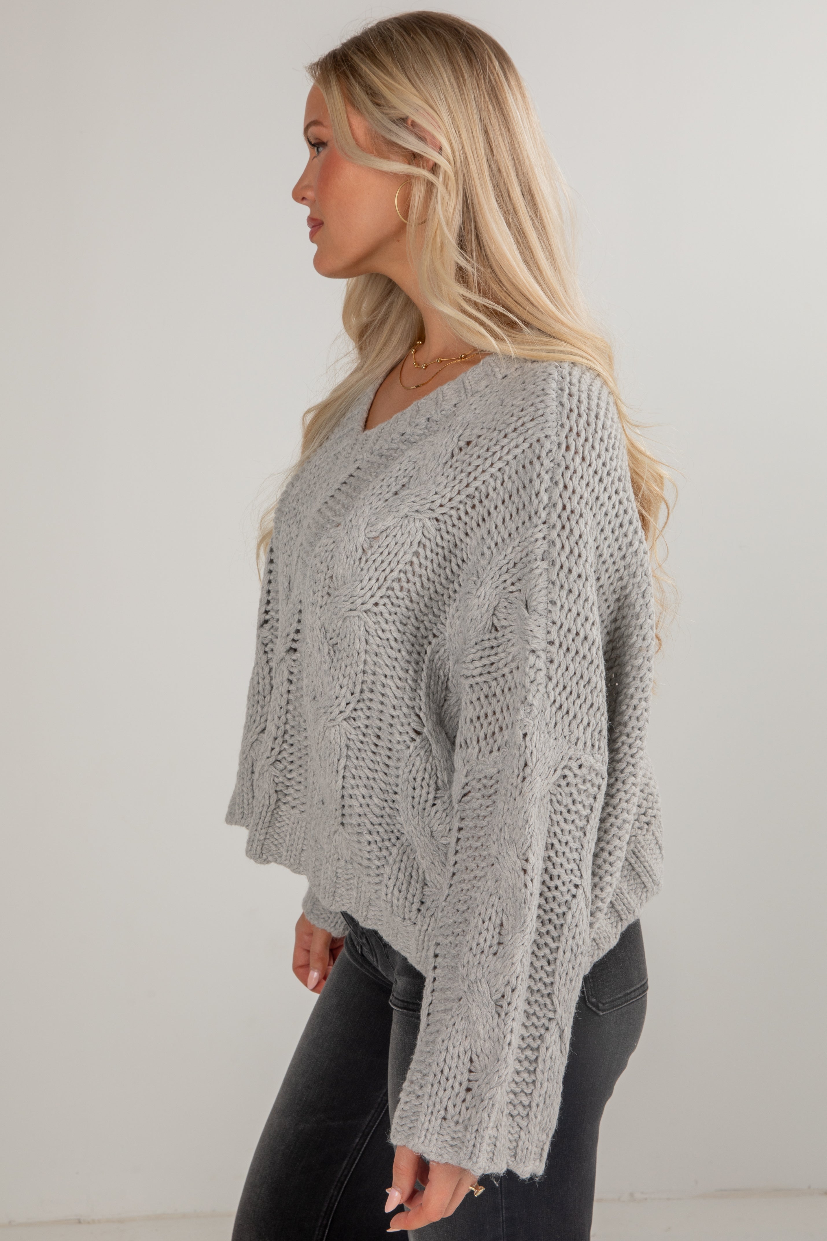 Woman wearing a gray knitted sweater against a white background