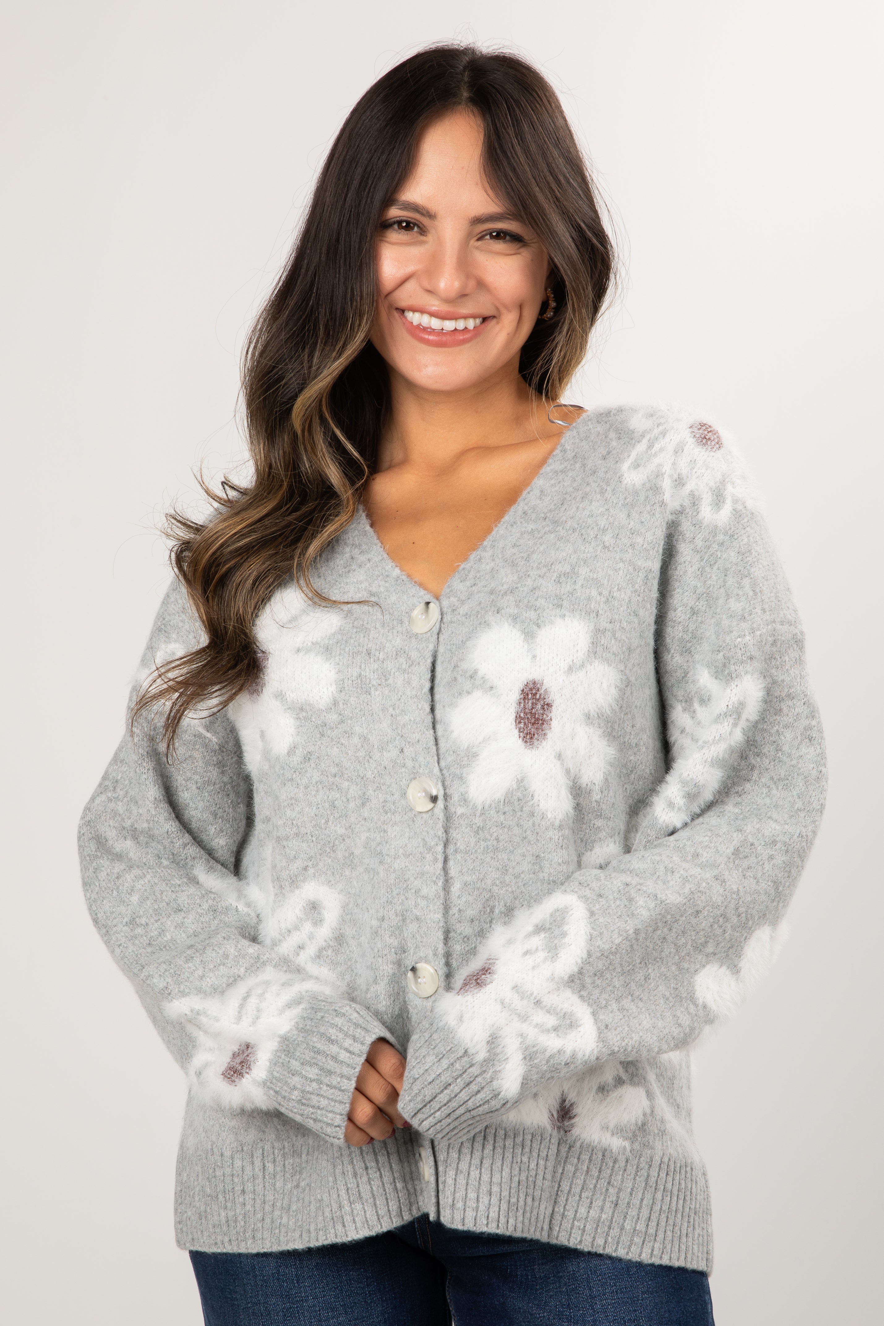 Woman wearing a gray cardigan with floral patterns on a white background