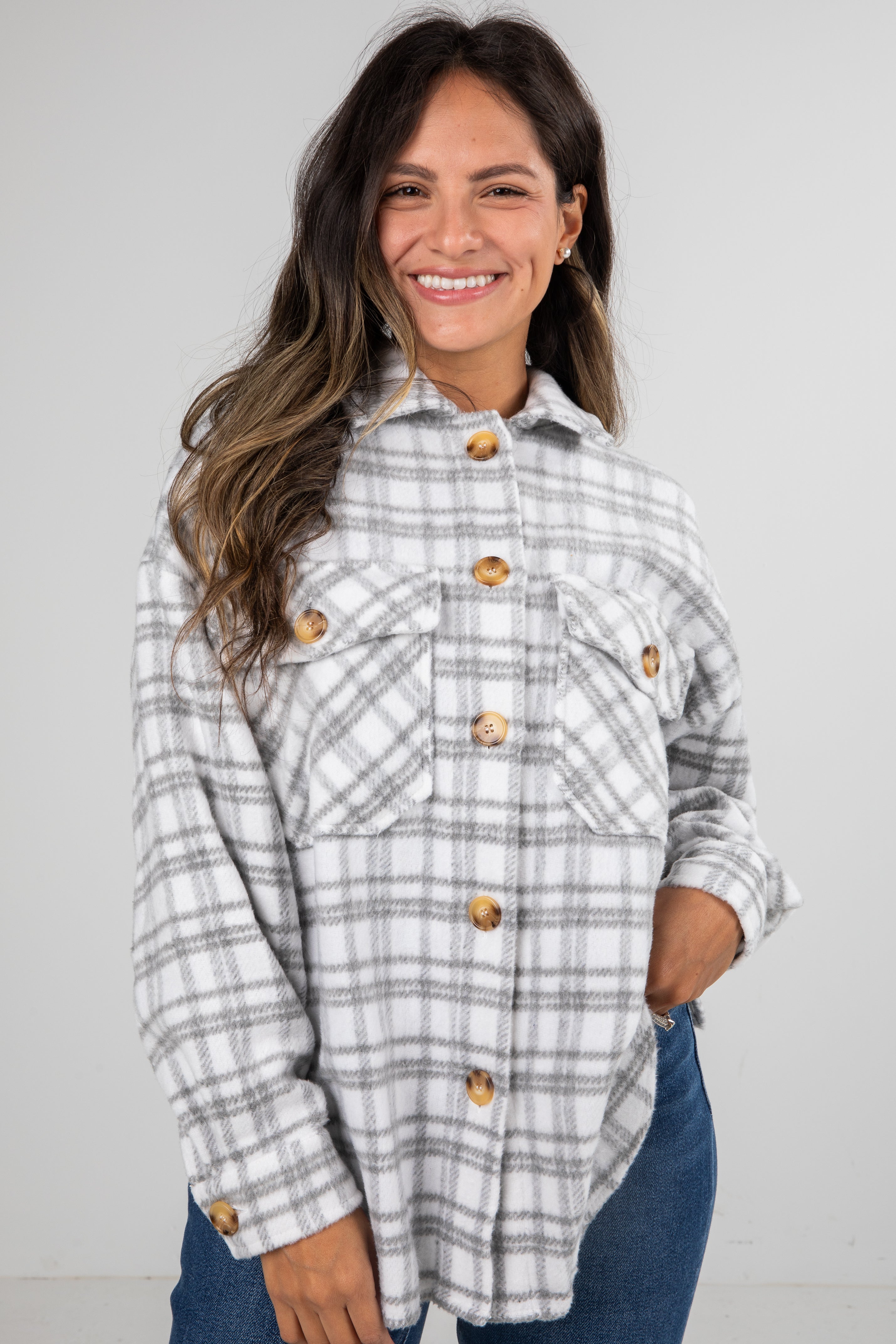 Woman wearing a plaid shirt with gold buttons against a plain background