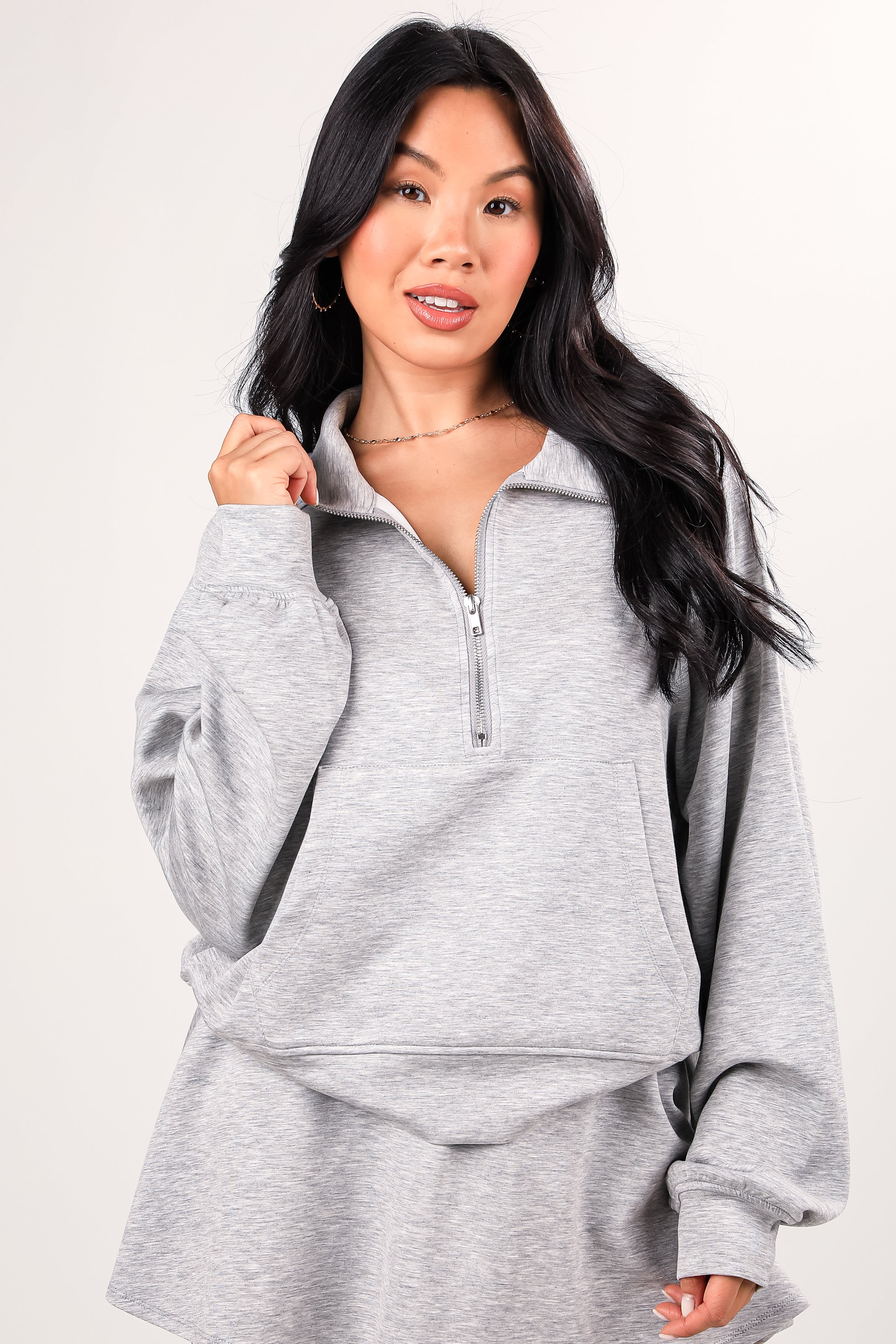 Woman wearing a gray pullover with a zipper on a white background