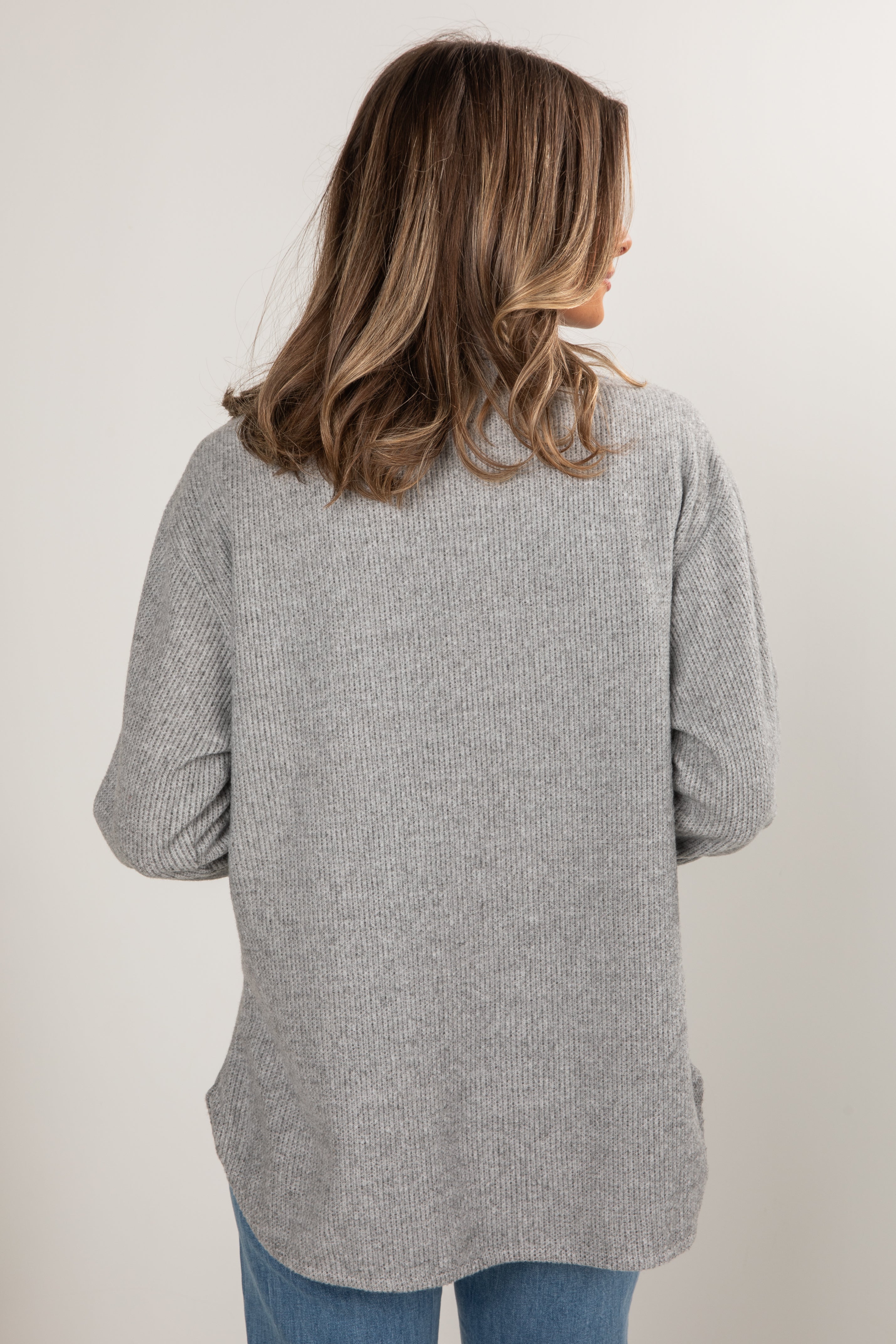 Person wearing a gray cardigan against a white background