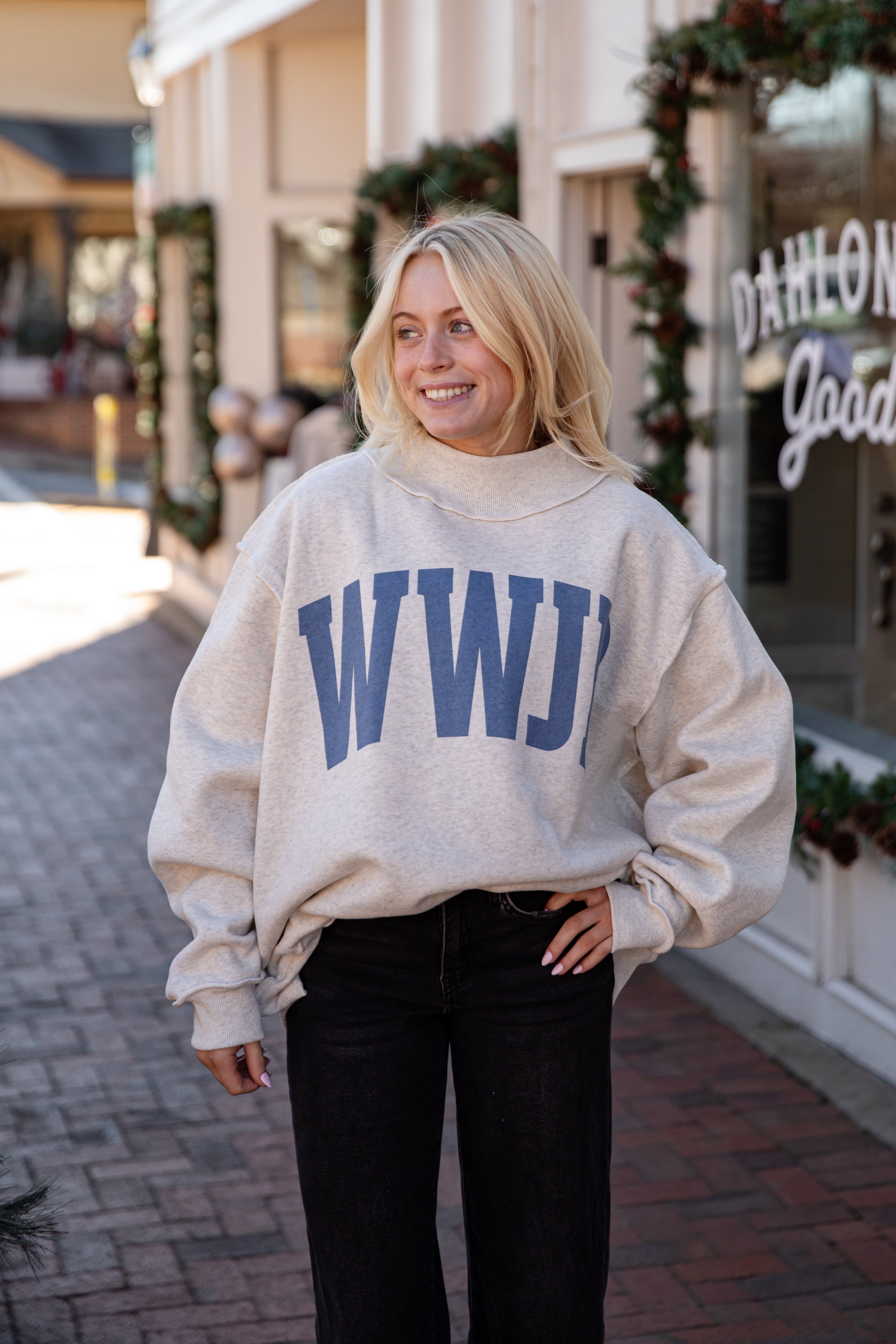 Woman wearing a beige sweatshirt with &