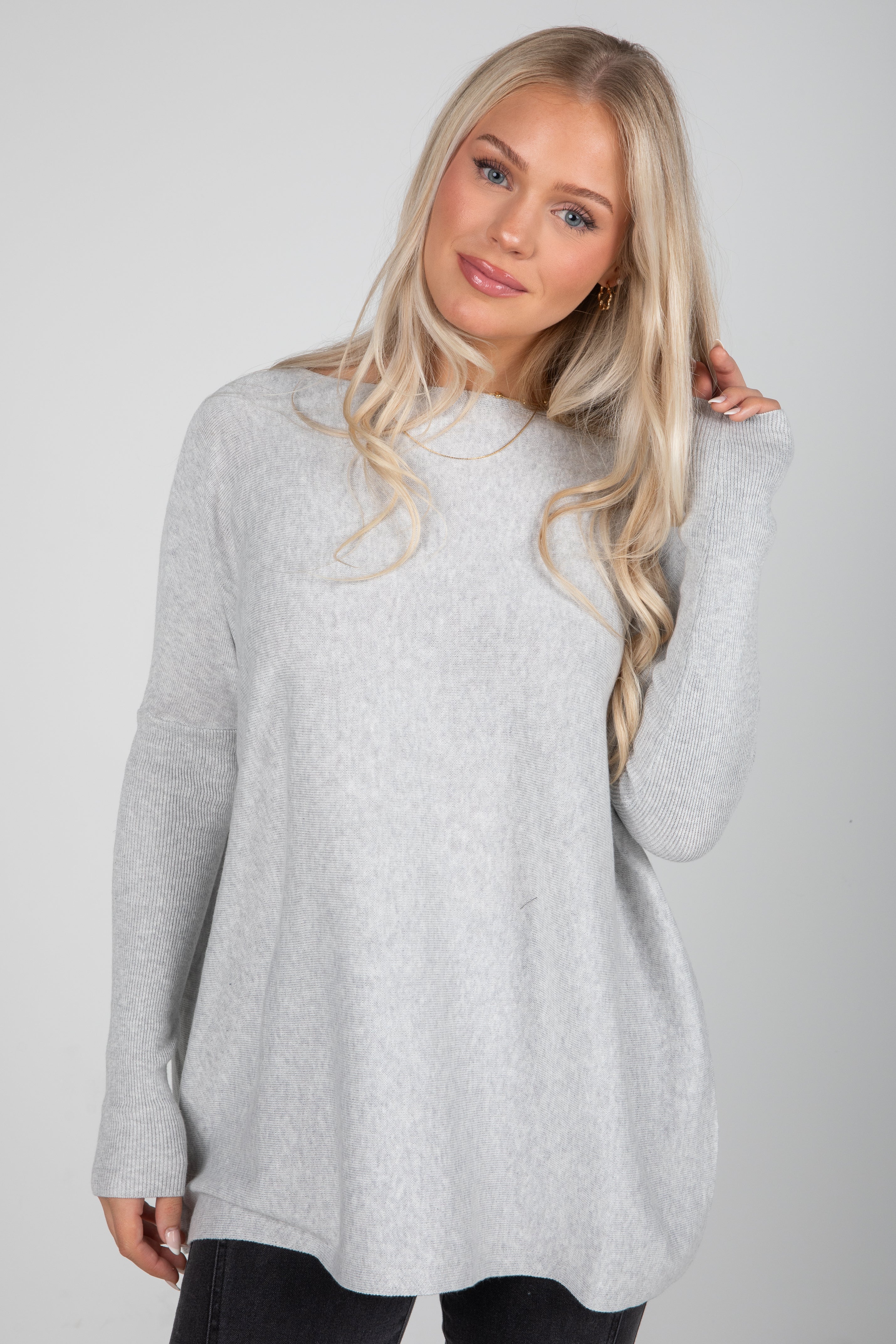 Woman wearing a gray sweater against a plain background