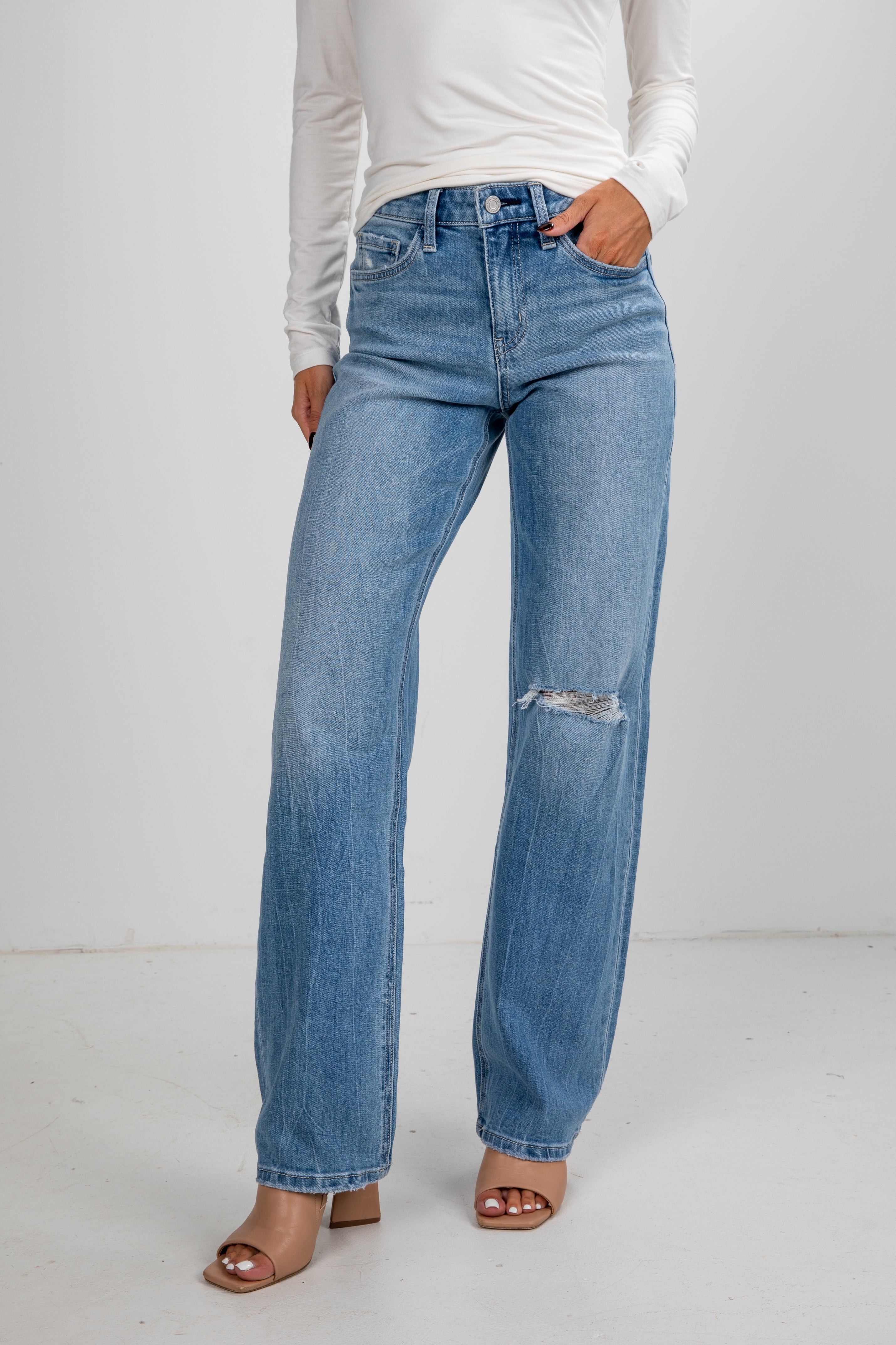 Person wearing light blue jeans with a white background