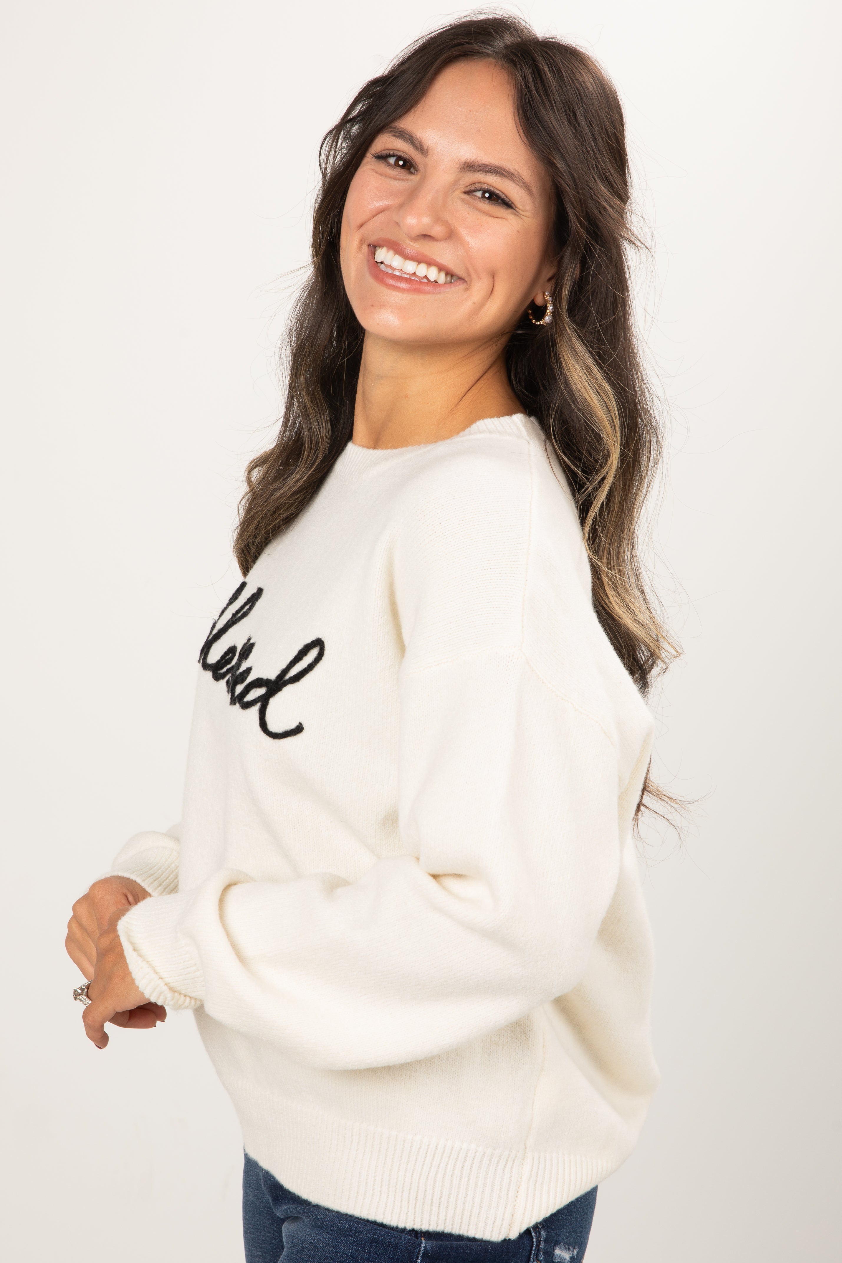 Woman wearing a white sweater with &