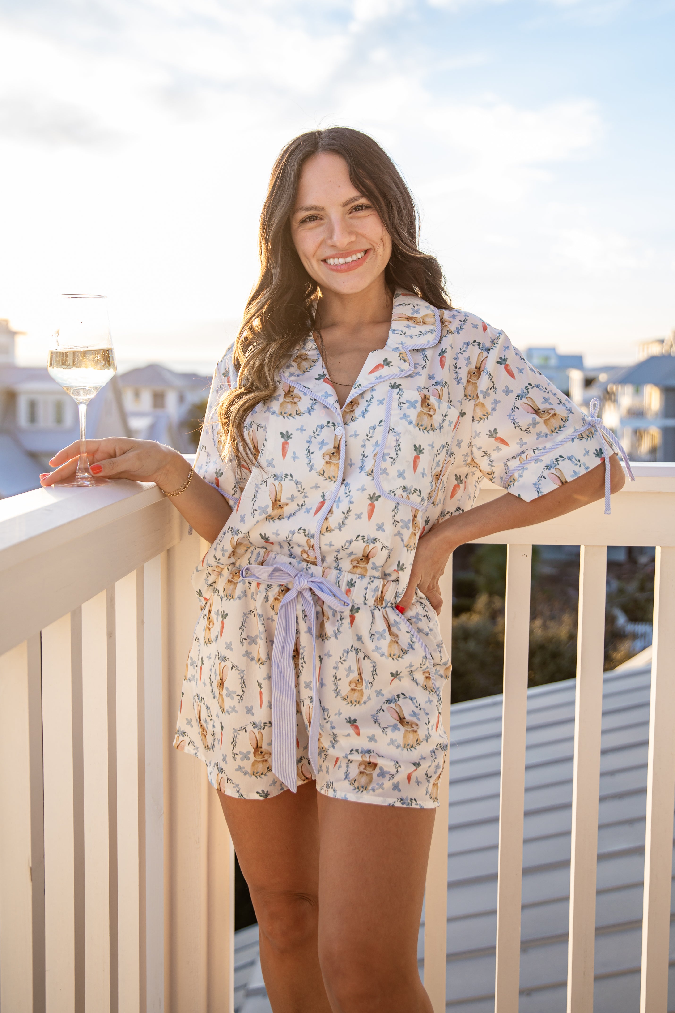 Woman in a floral dress standing on a balcony with a cityscape in the background