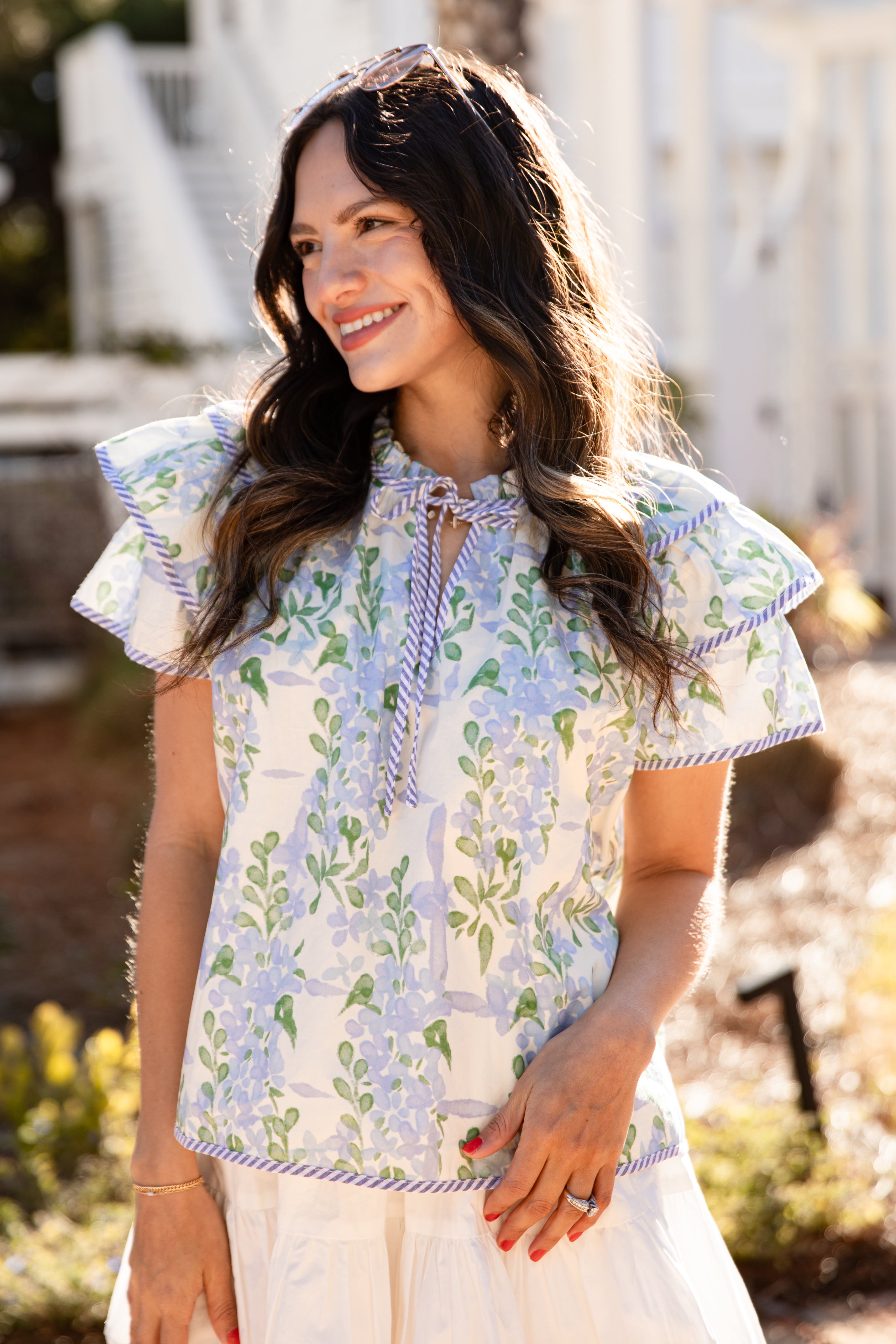Woman wearing a floral blouse with ruffled sleeves outdoors.
