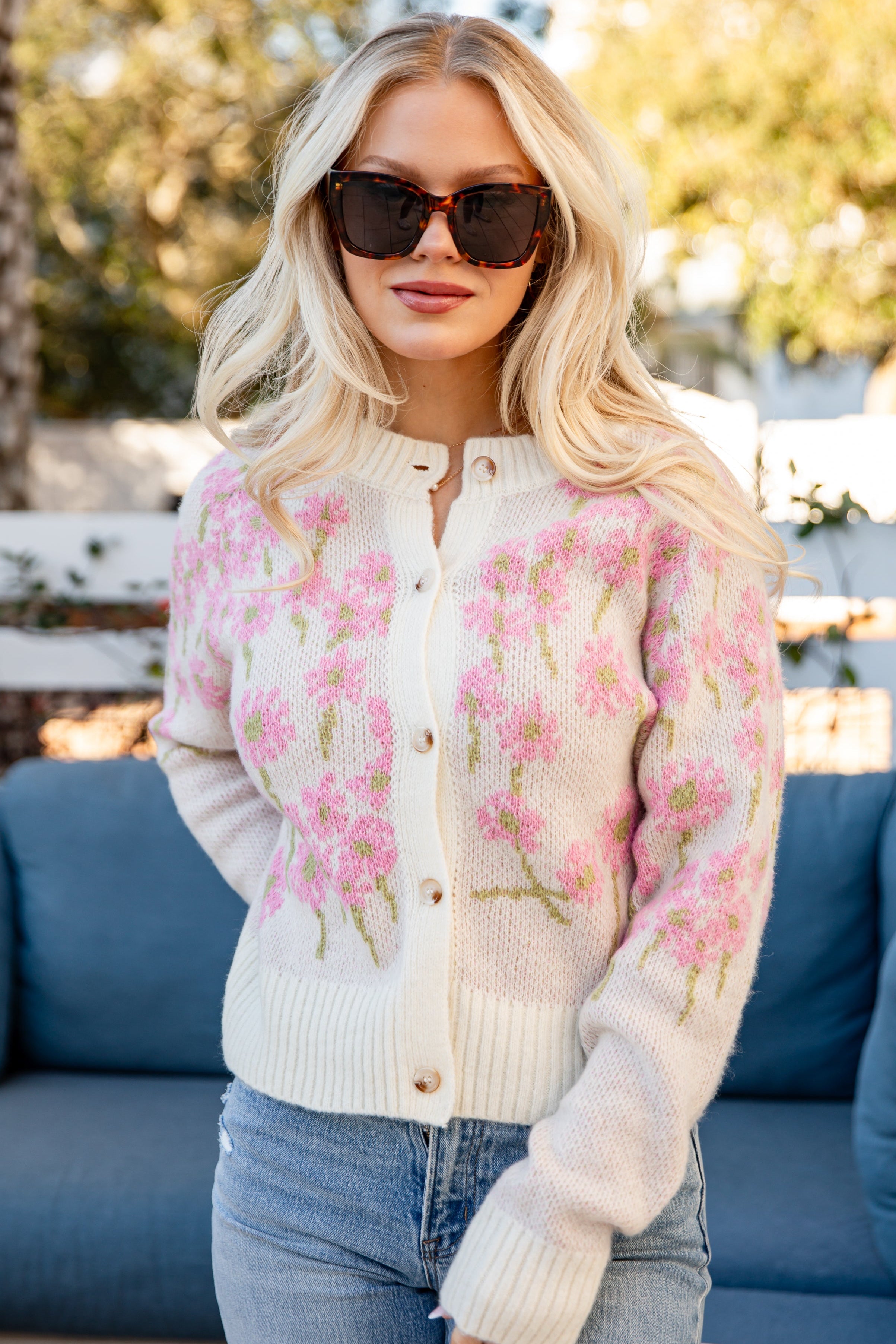 Woman wearing a floral cardigan with a blurred outdoor background