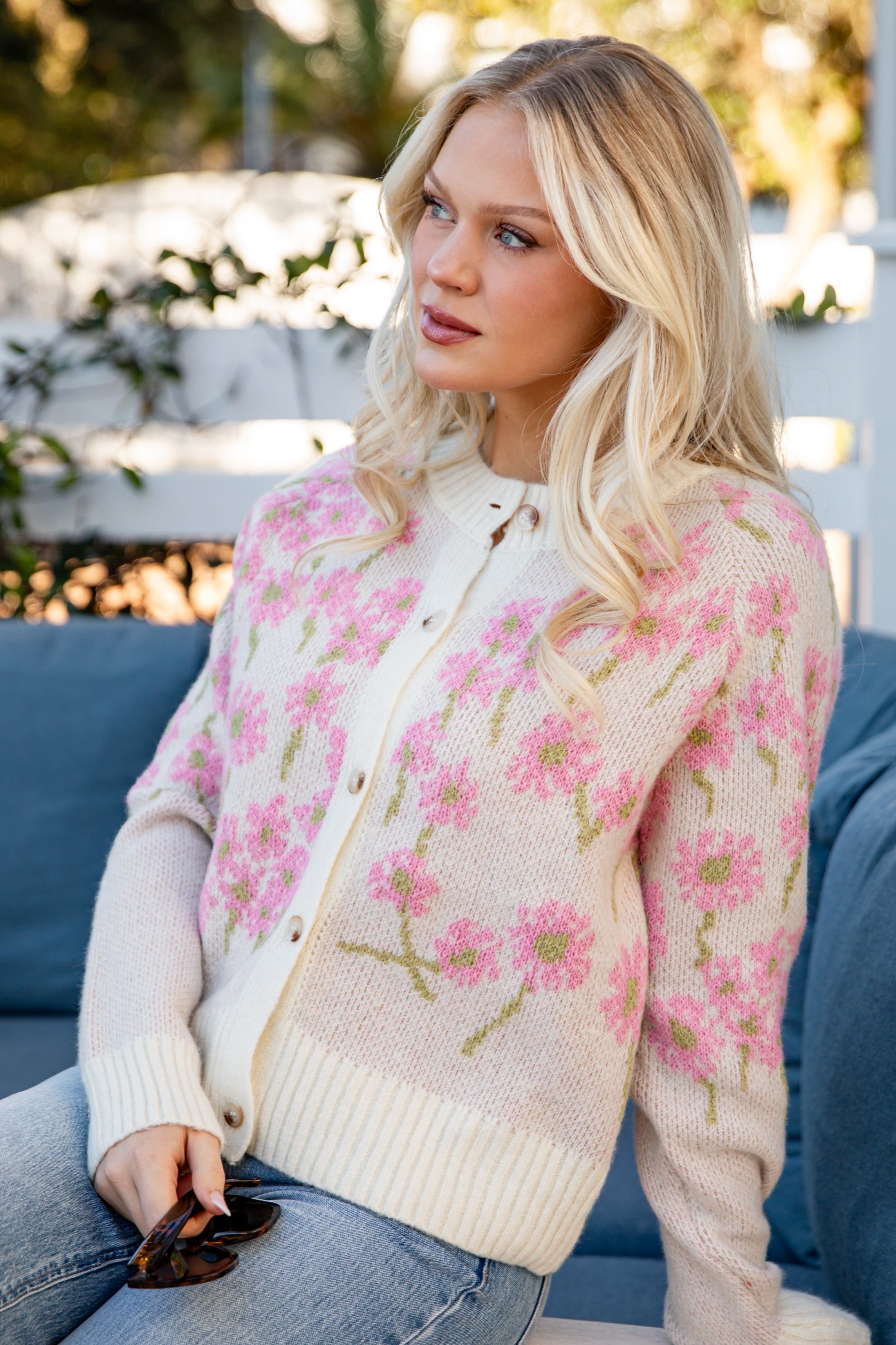 Woman wearing a floral sweater sitting on a blue couch outdoors.