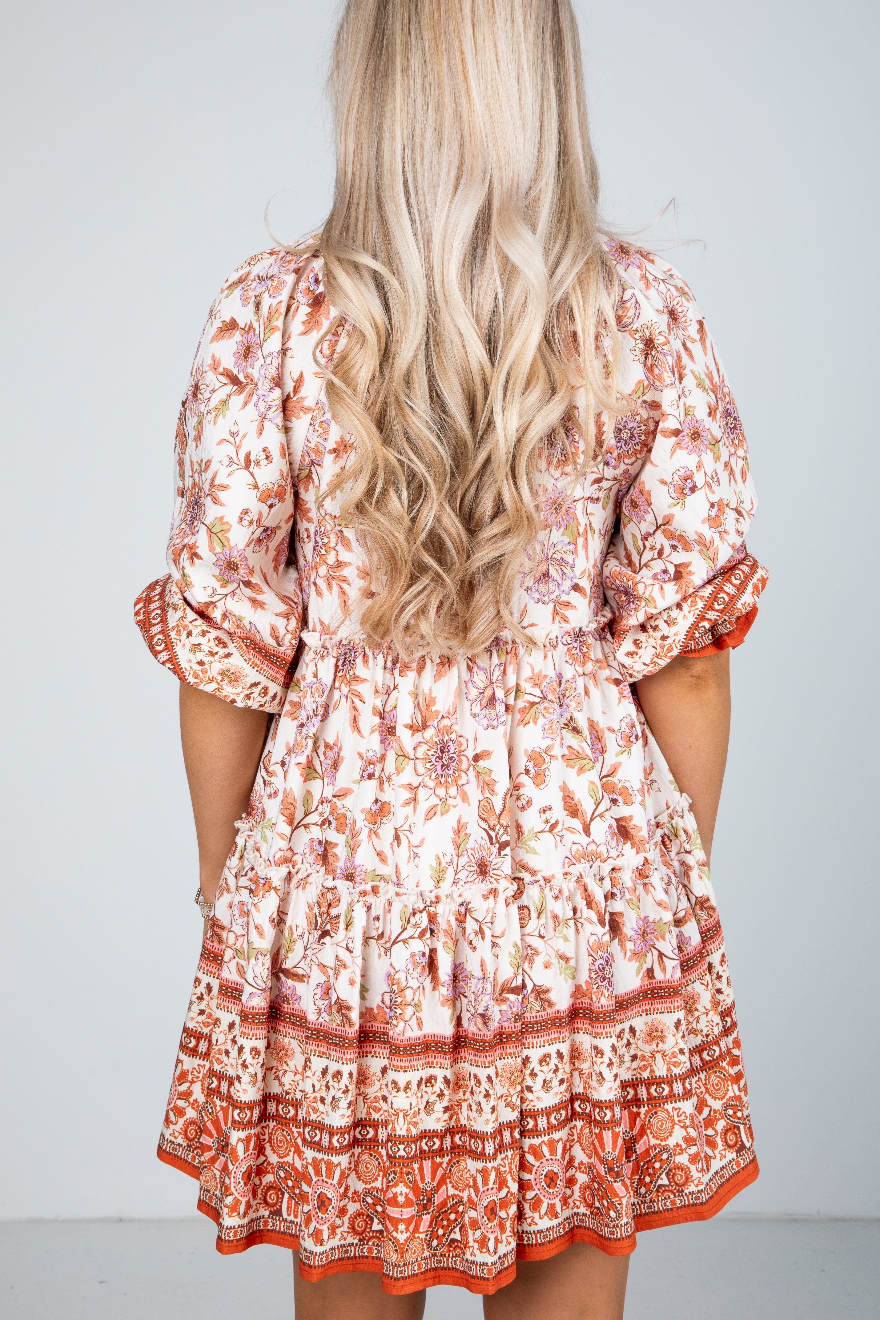 Woman wearing a patterned dress with long blonde hair on a plain background