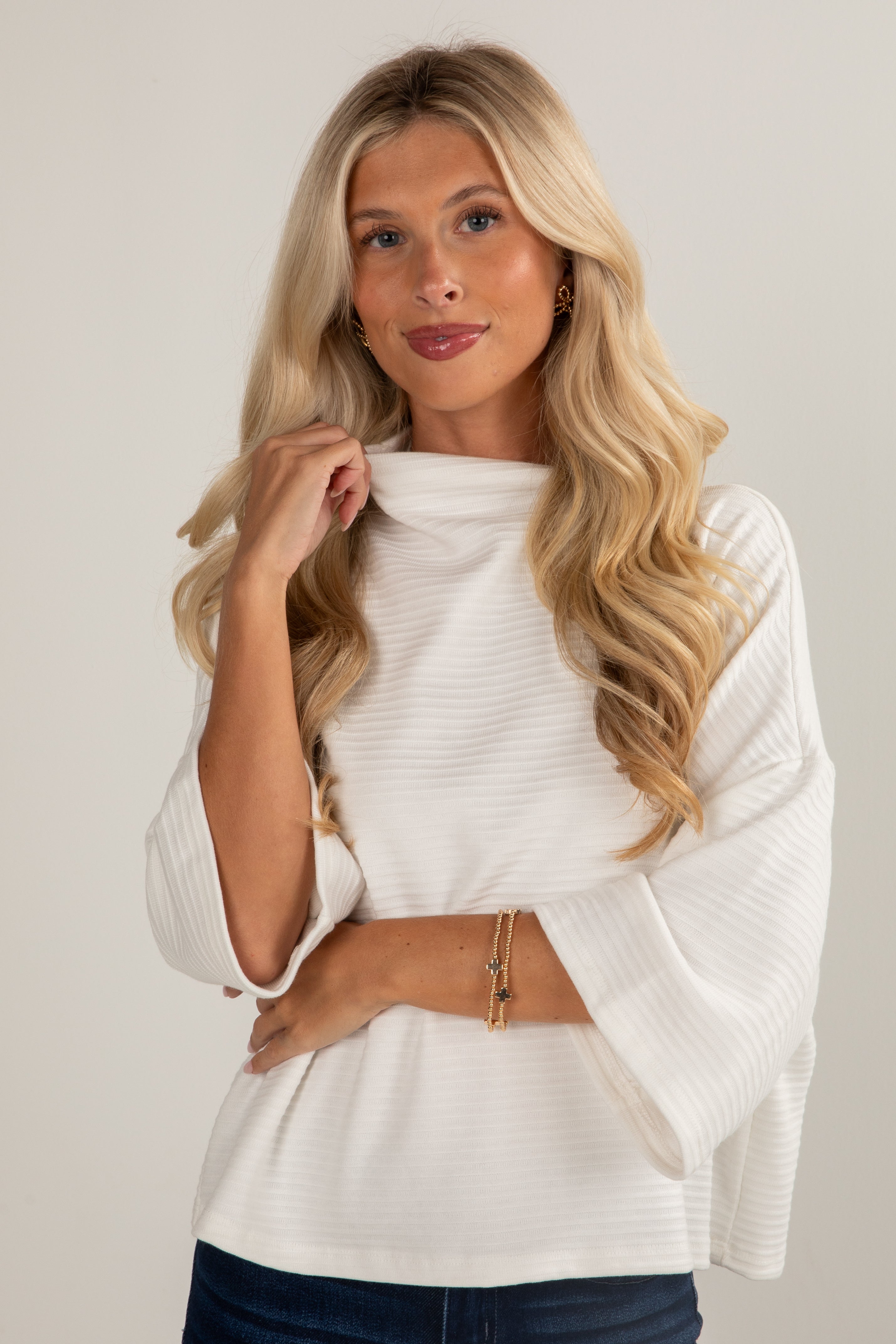 Woman wearing a white sweater against a plain background