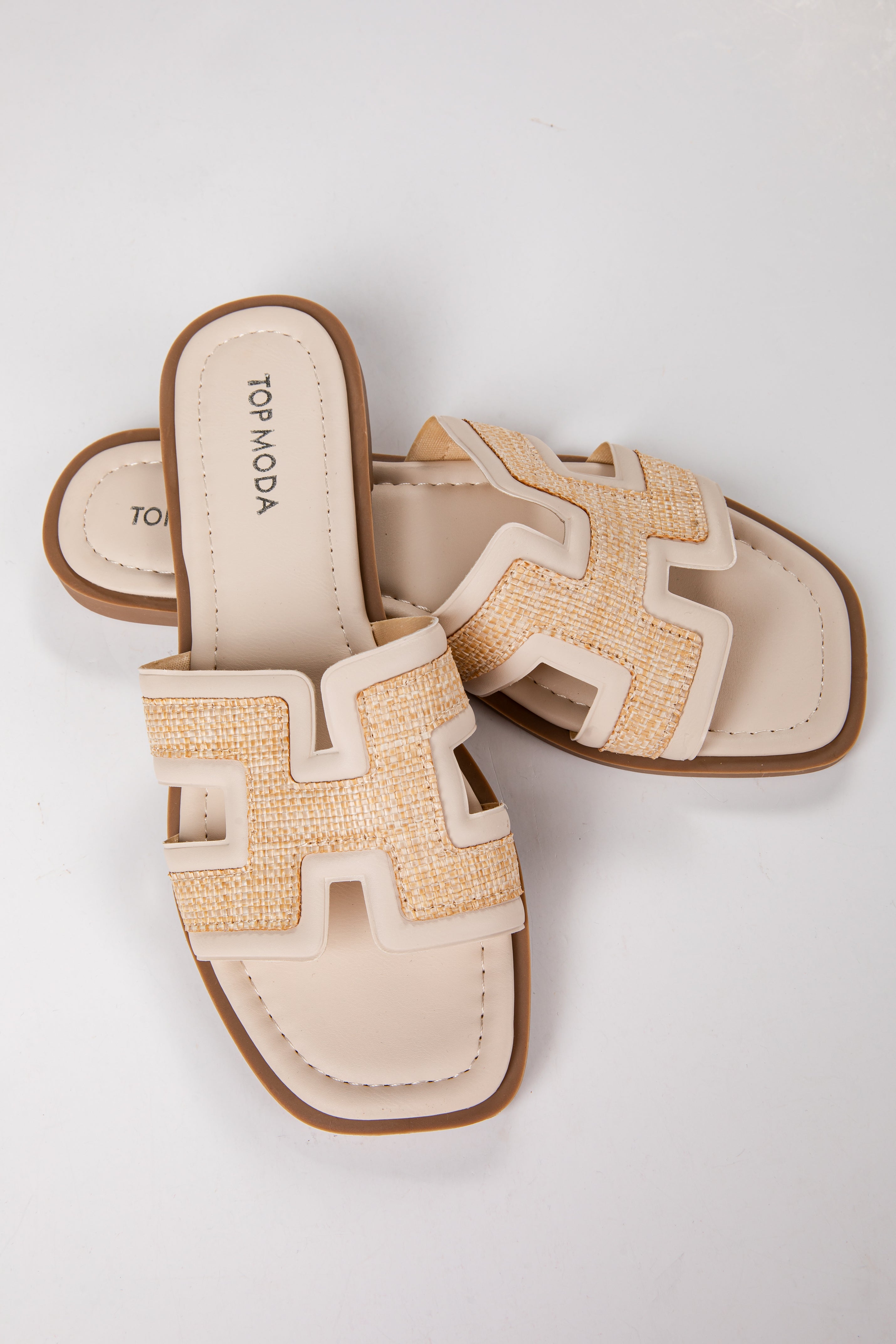 Pair of beige sandals with brown soles on a light gray background