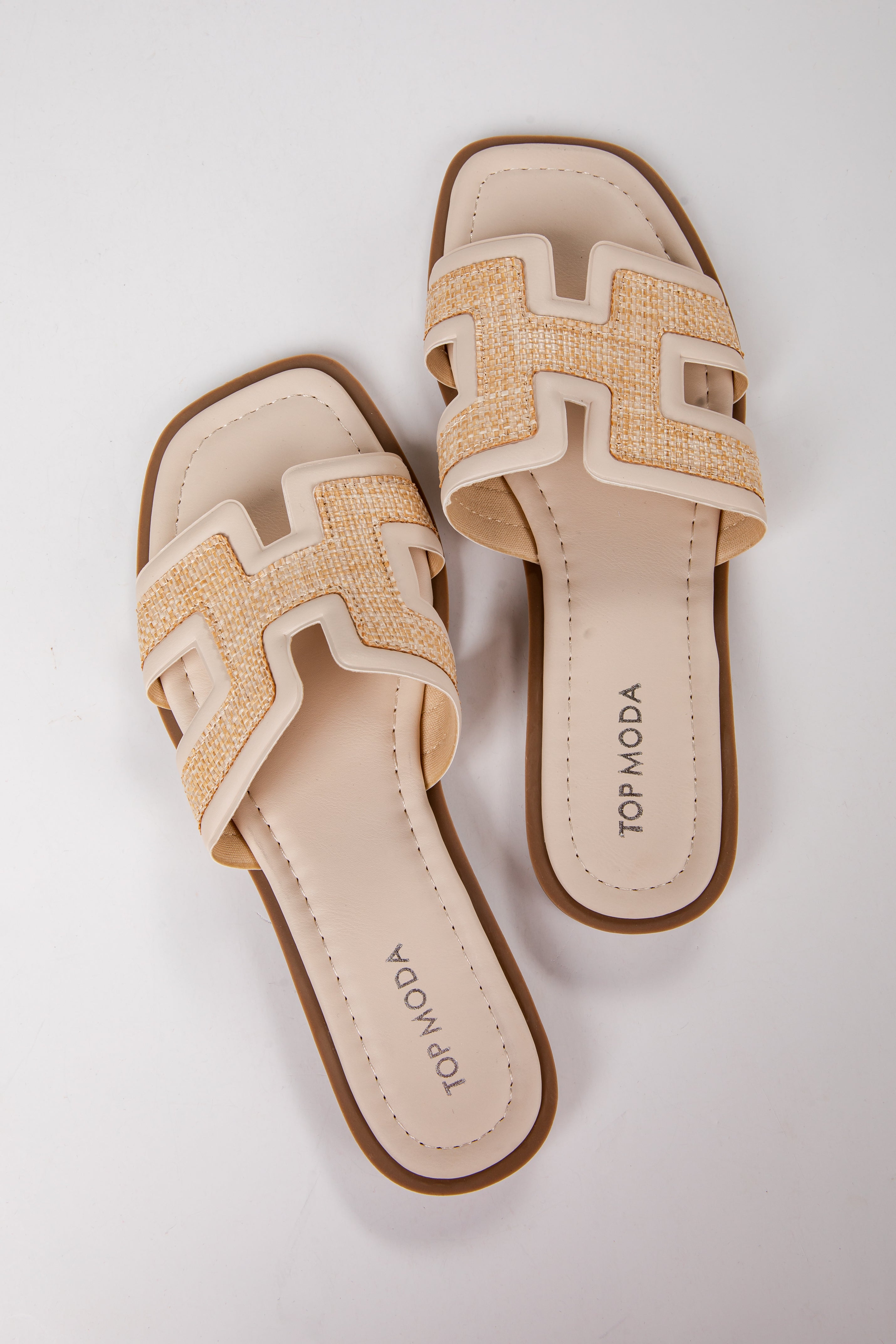 Pair of beige sandals with woven design on a white background