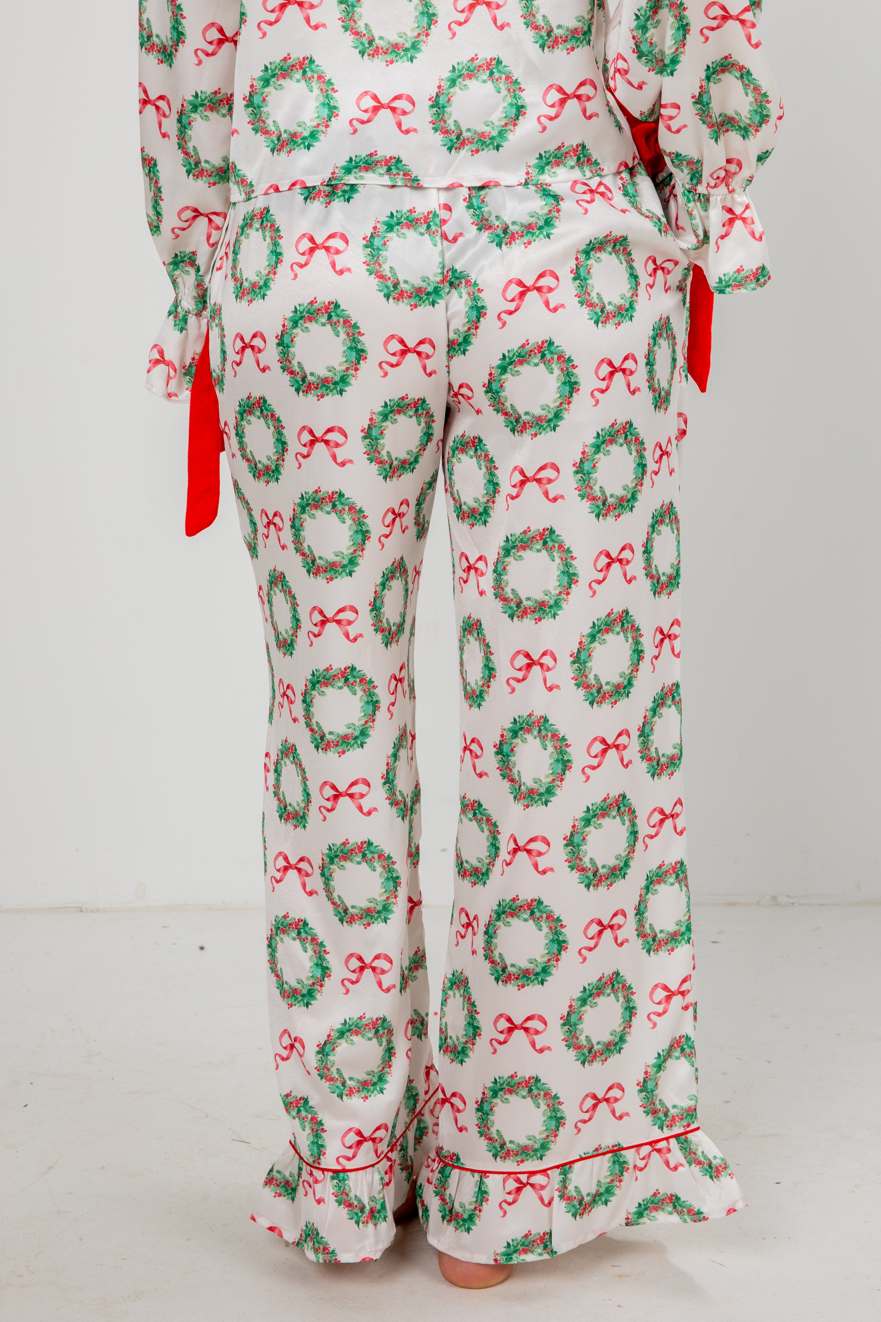 Pajama pants with Christmas wreath and bow pattern on a white background