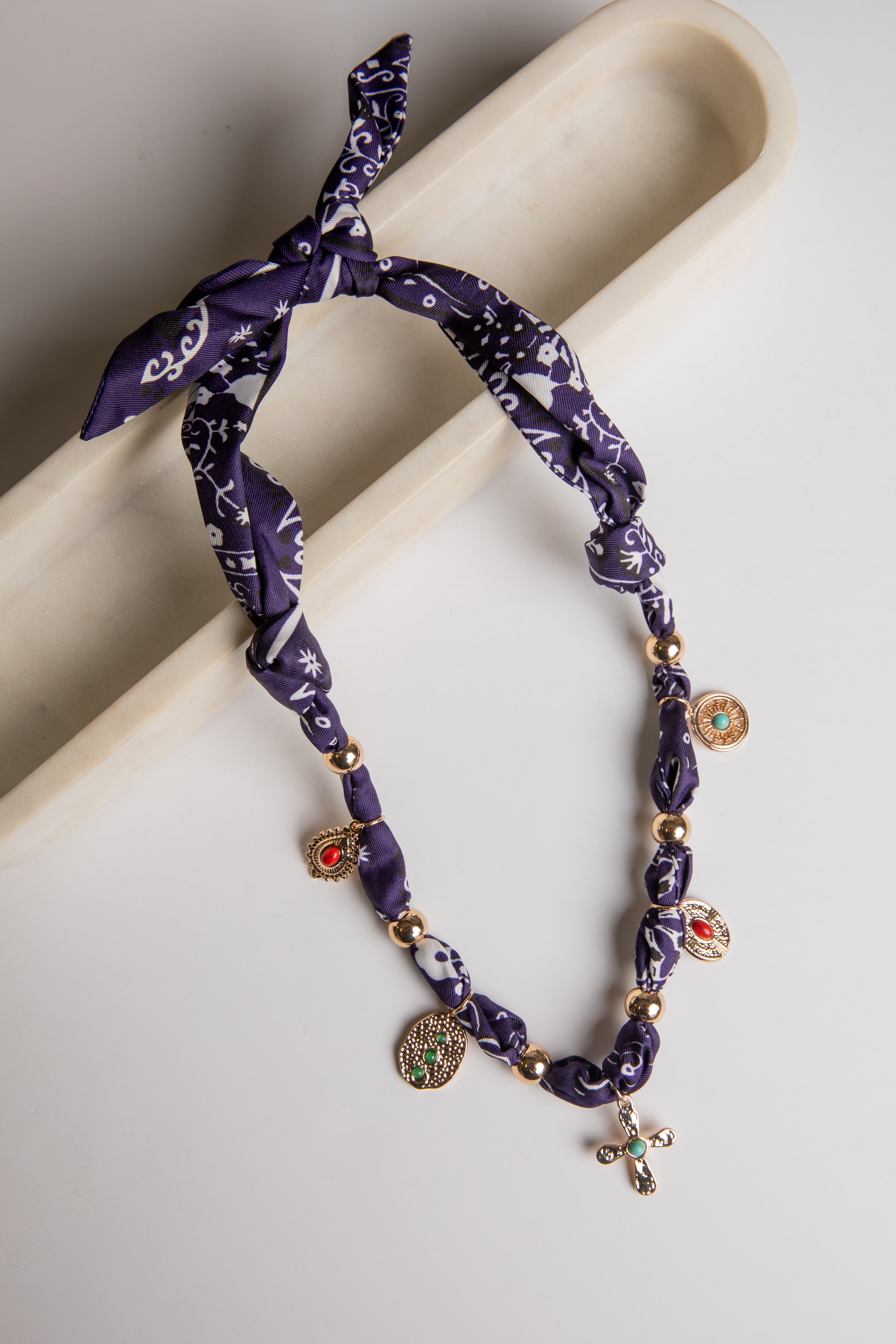 Purple patterned headband with gold beads and charms on a beige surface