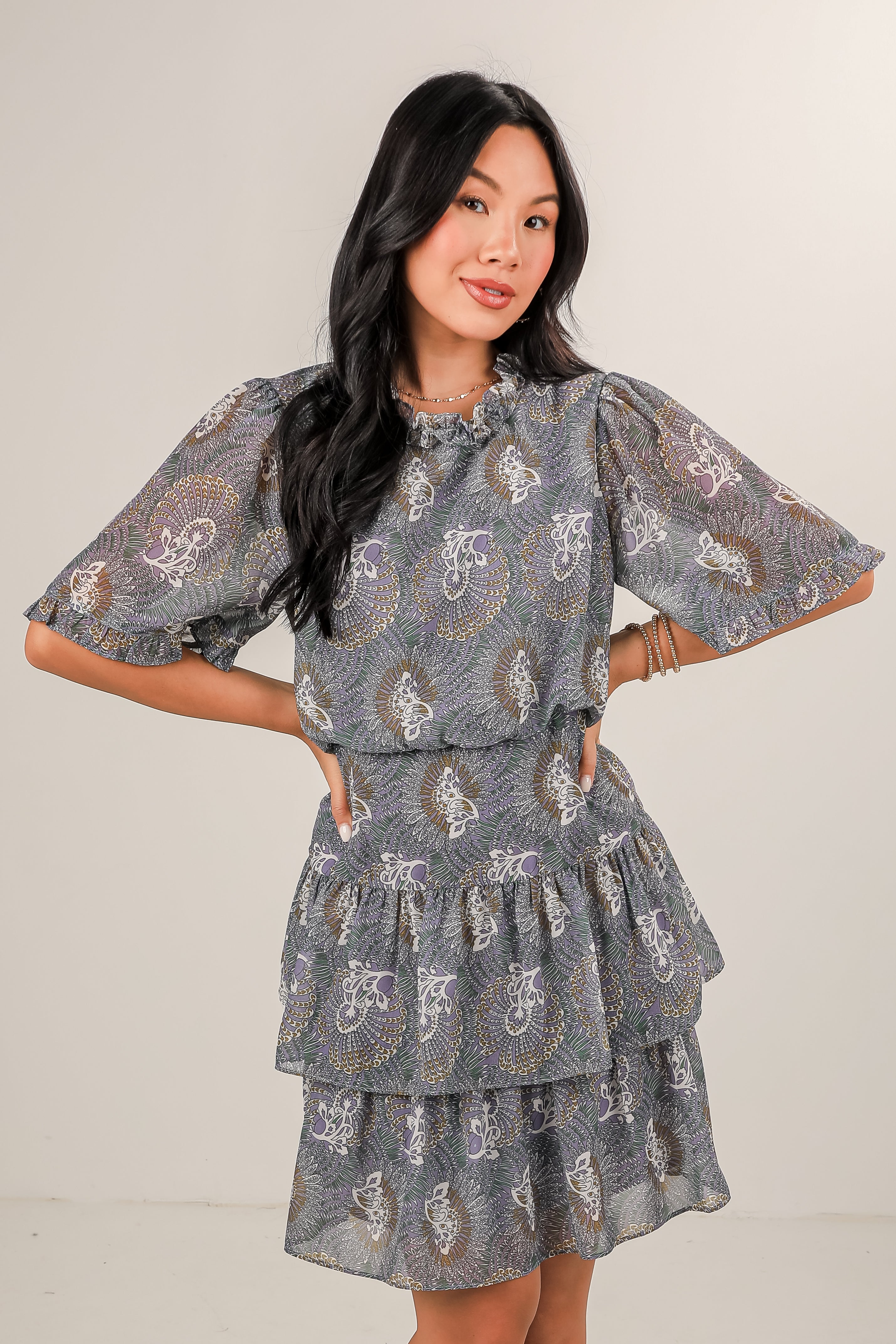 Woman wearing a gray patterned dress against a plain background