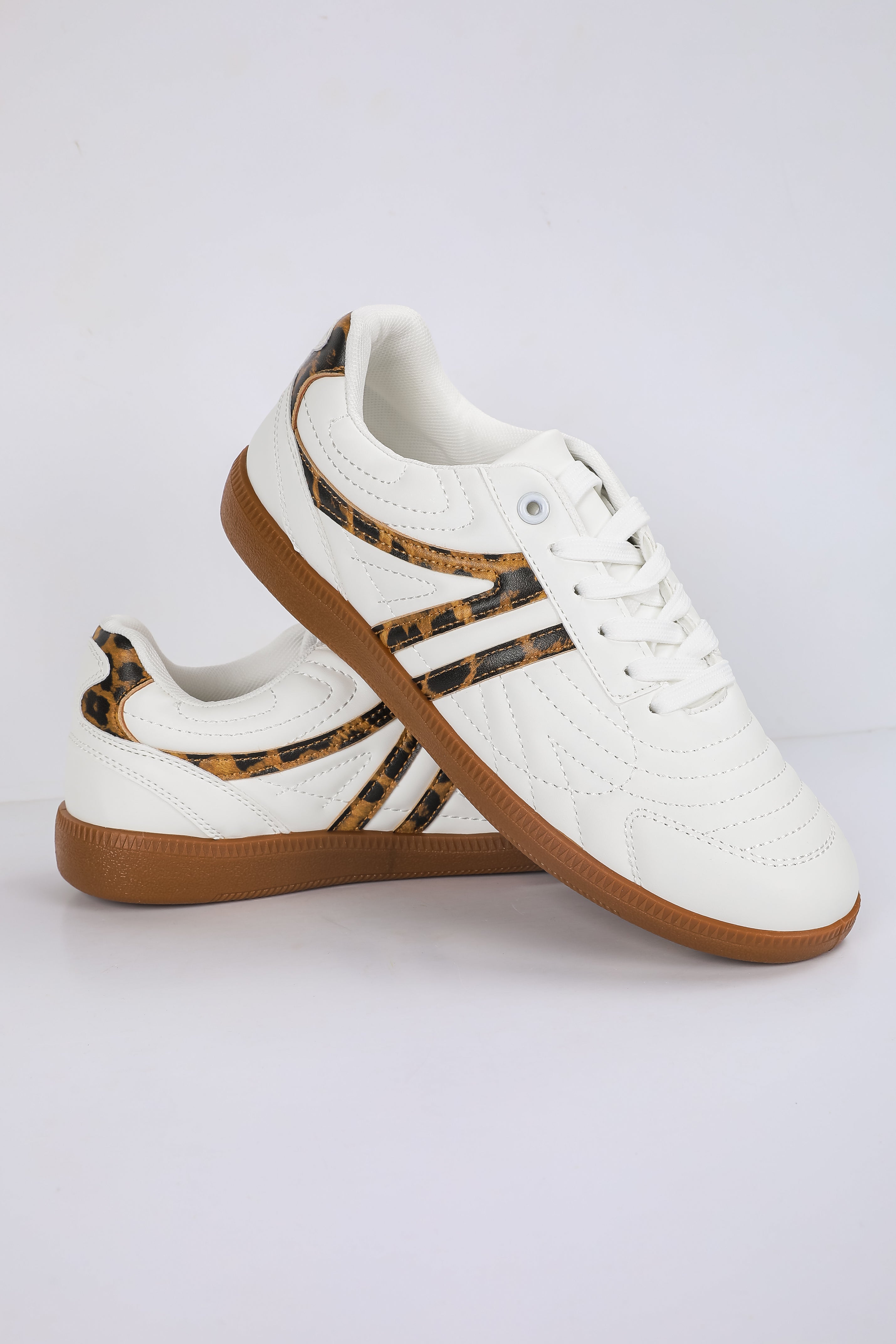 White sneakers with brown soles on a light gray background