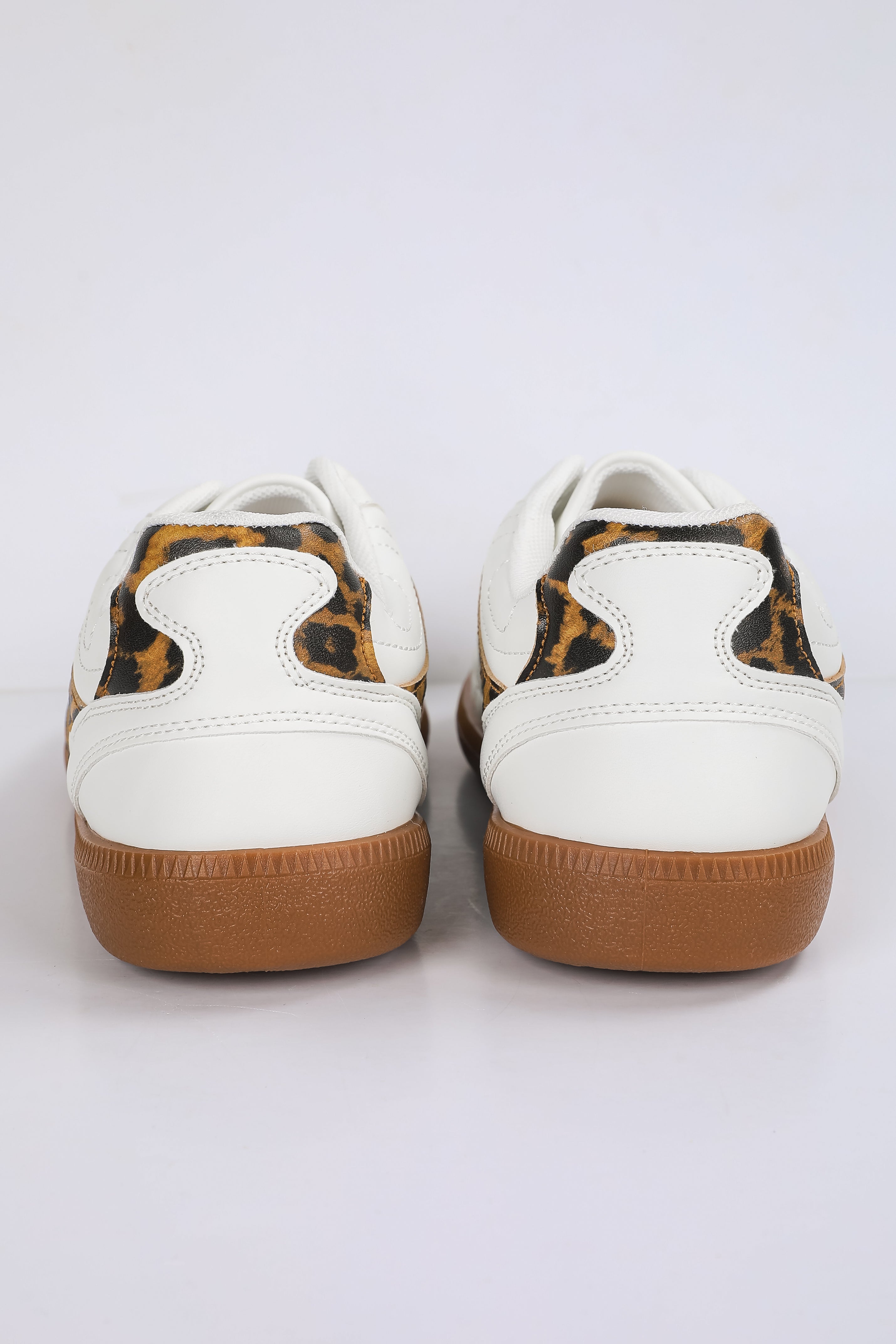 White sneakers with brown soles and leopard print accents on a white background
