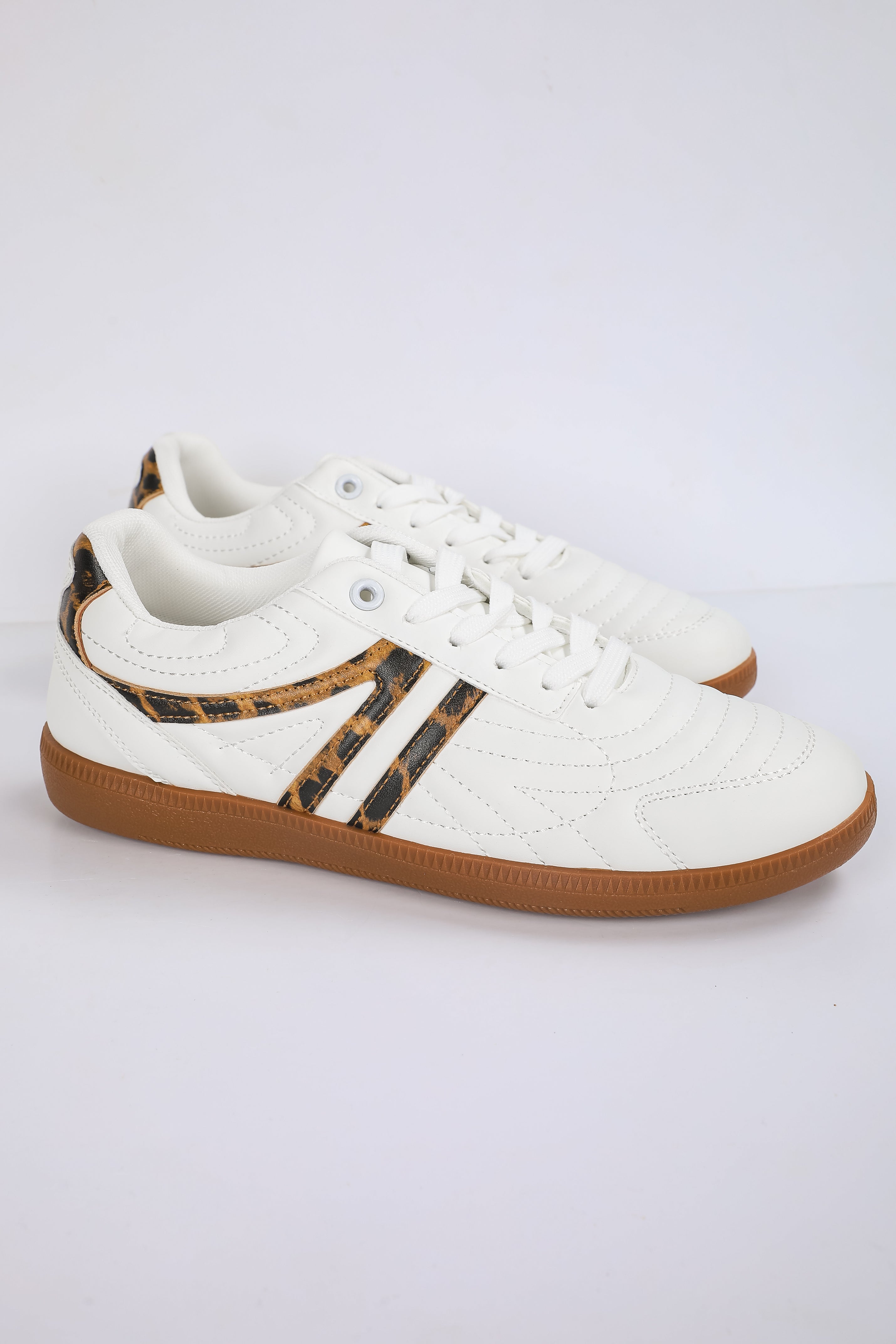 White sneaker with brown sole and leopard print accents on a light gray background