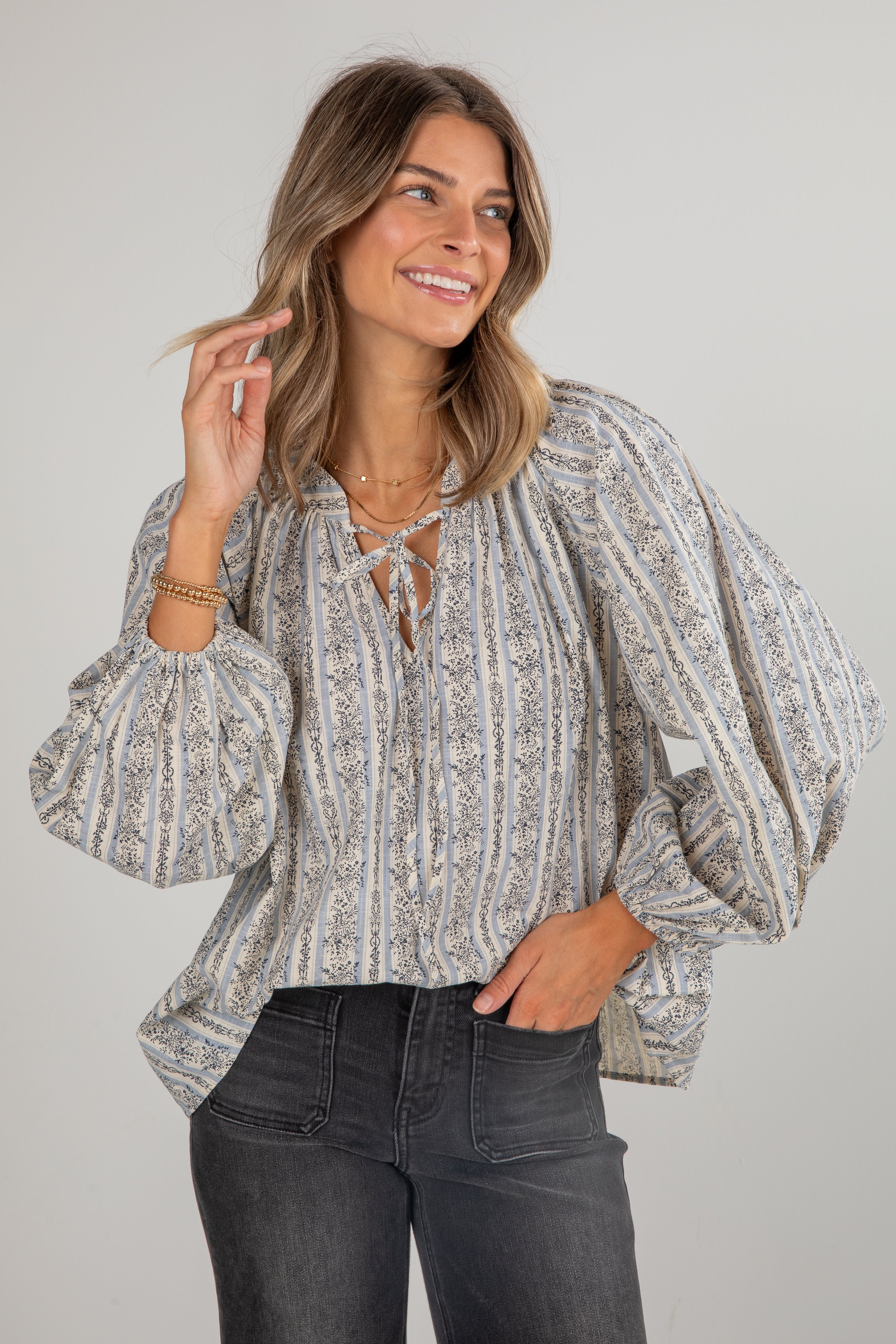 Woman wearing a patterned blouse with puff sleeves against a plain background