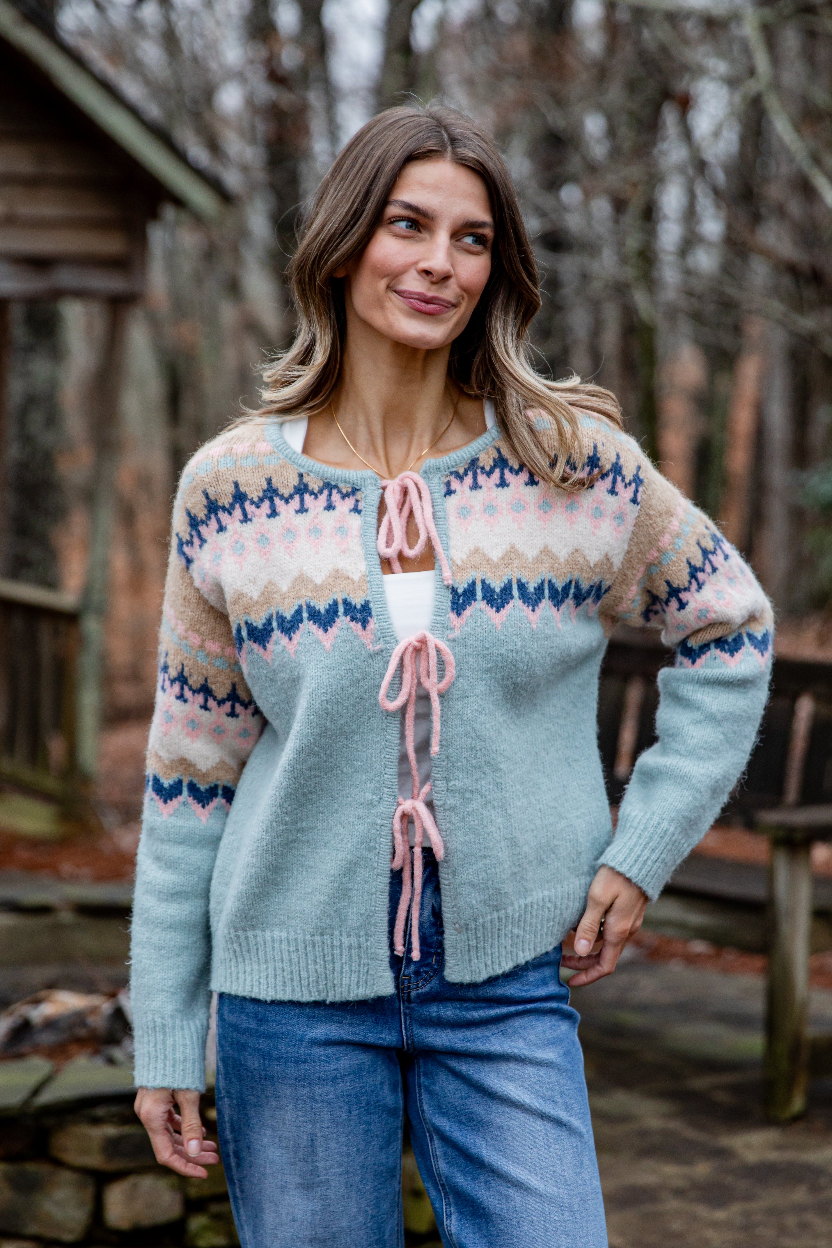 Woman wearing a patterned sweater with pink accents outdoors.