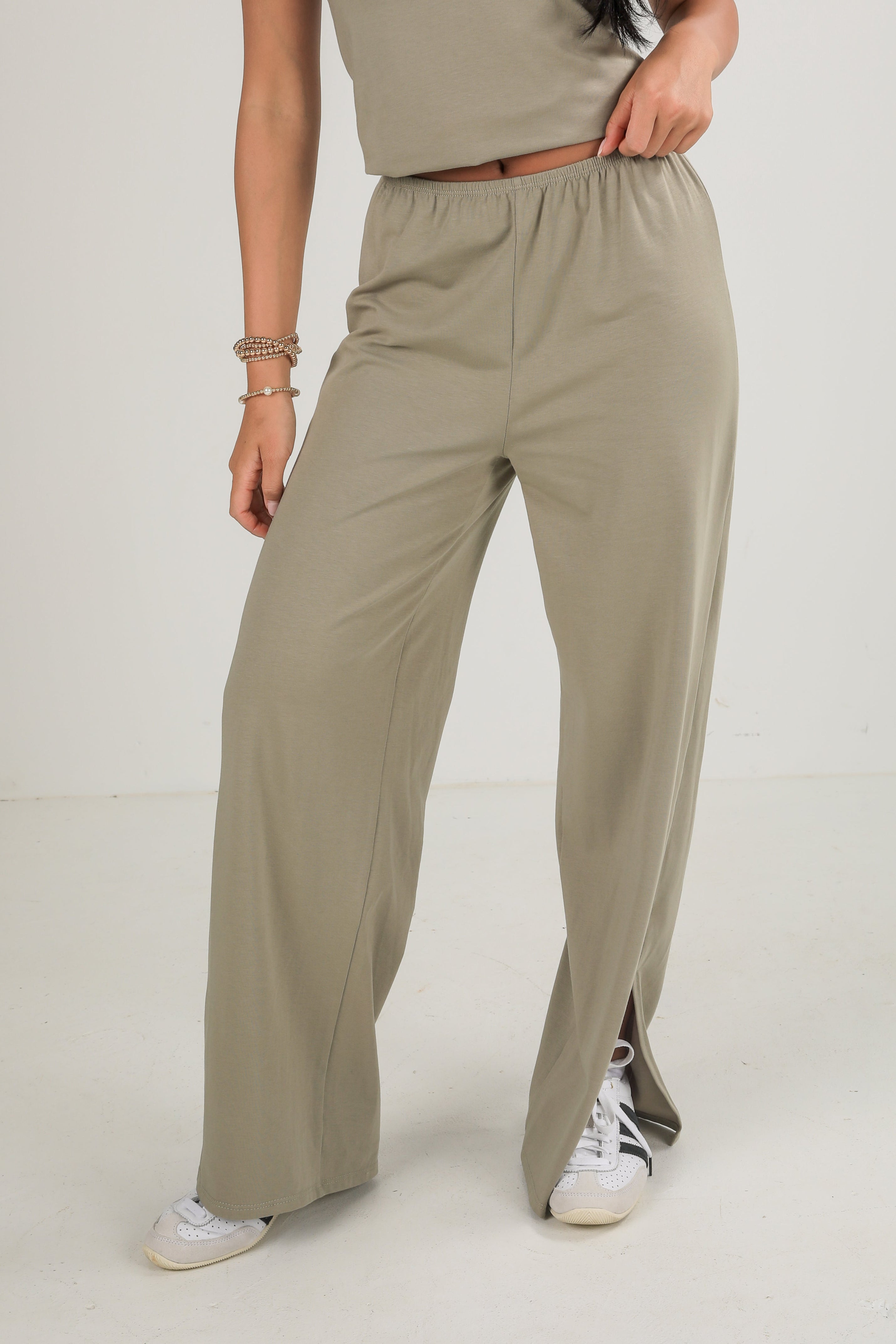 Person wearing beige wide-leg pants on a white background