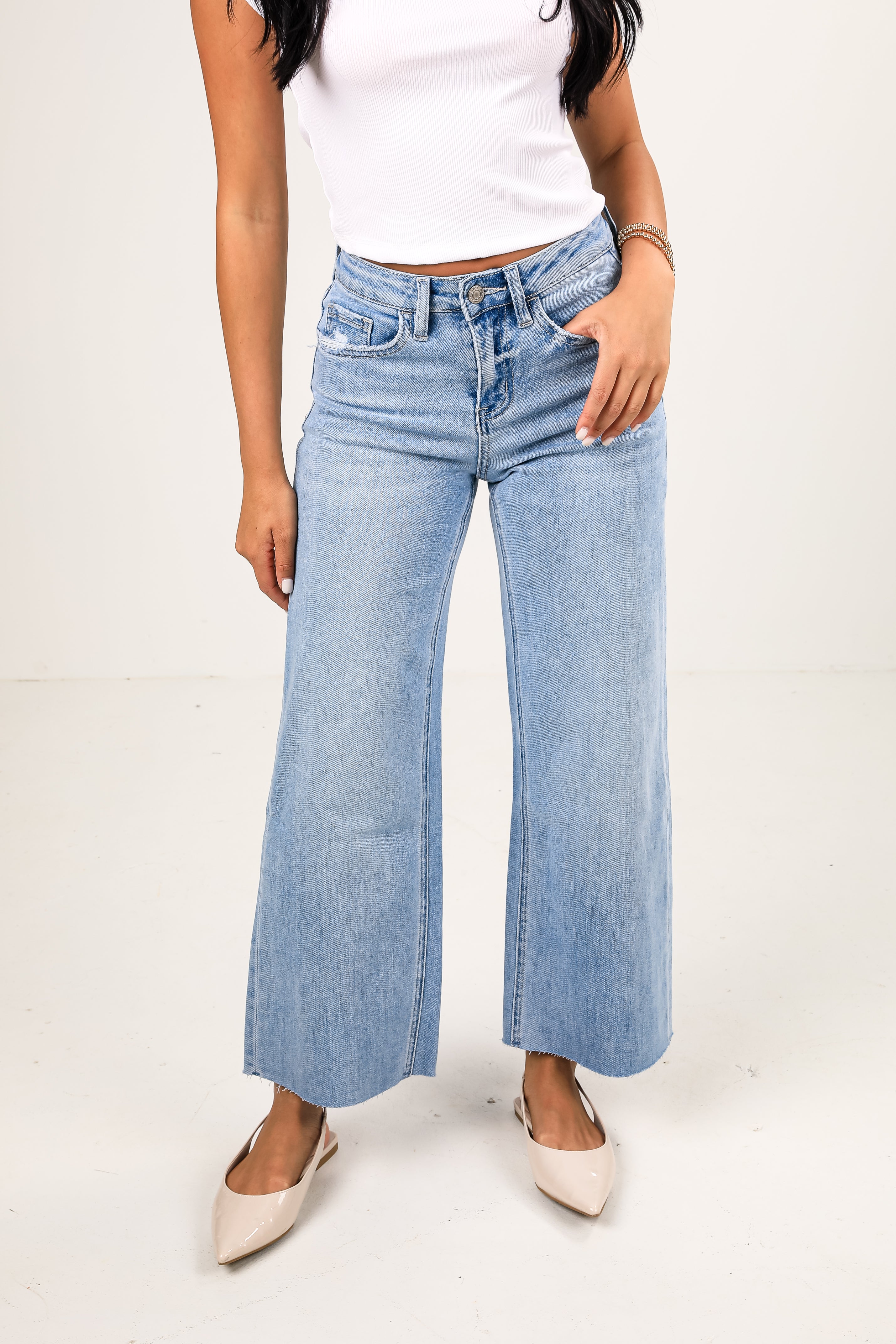 Person wearing light blue wide-leg jeans on a white background