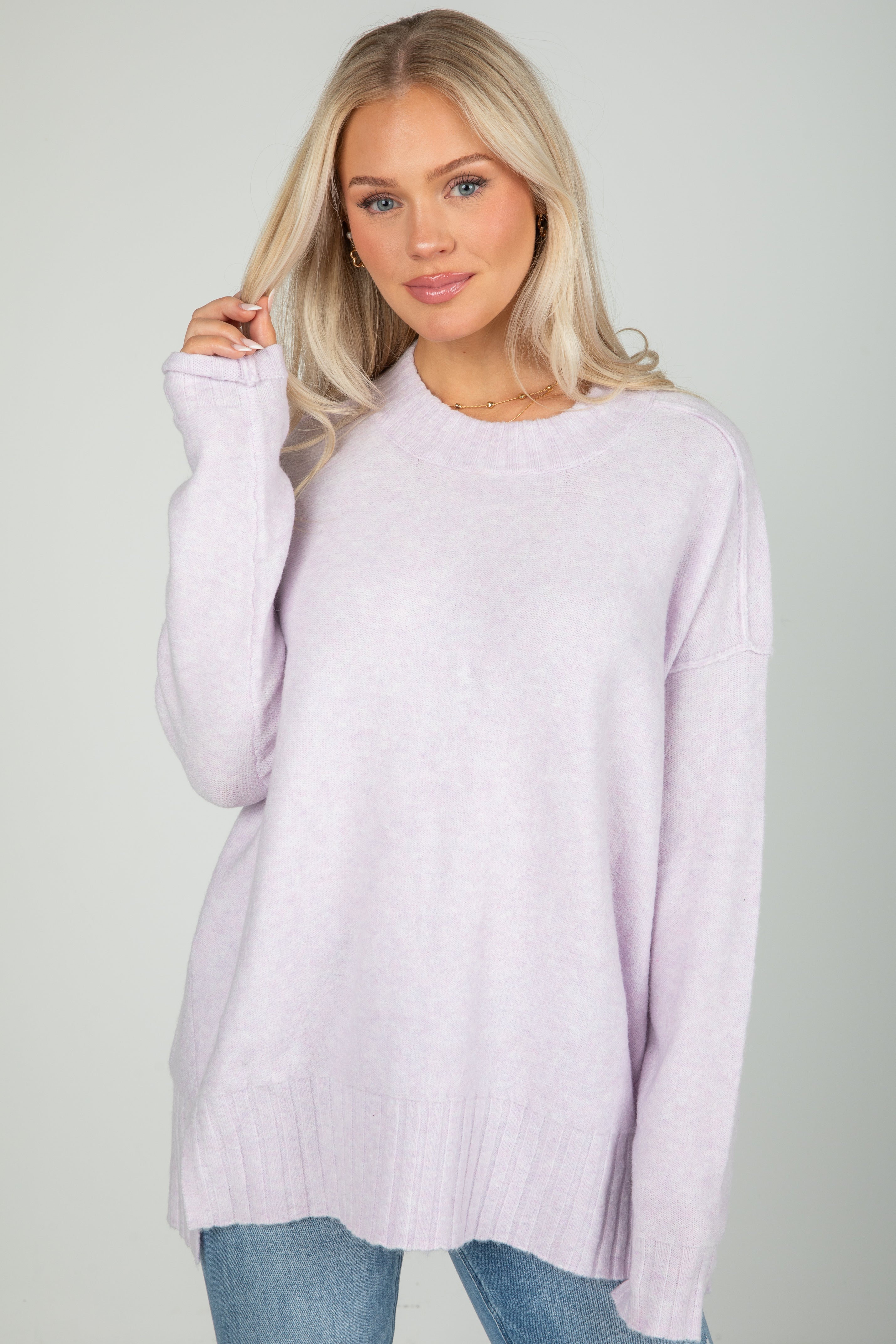 Woman wearing a light purple sweater against a plain background