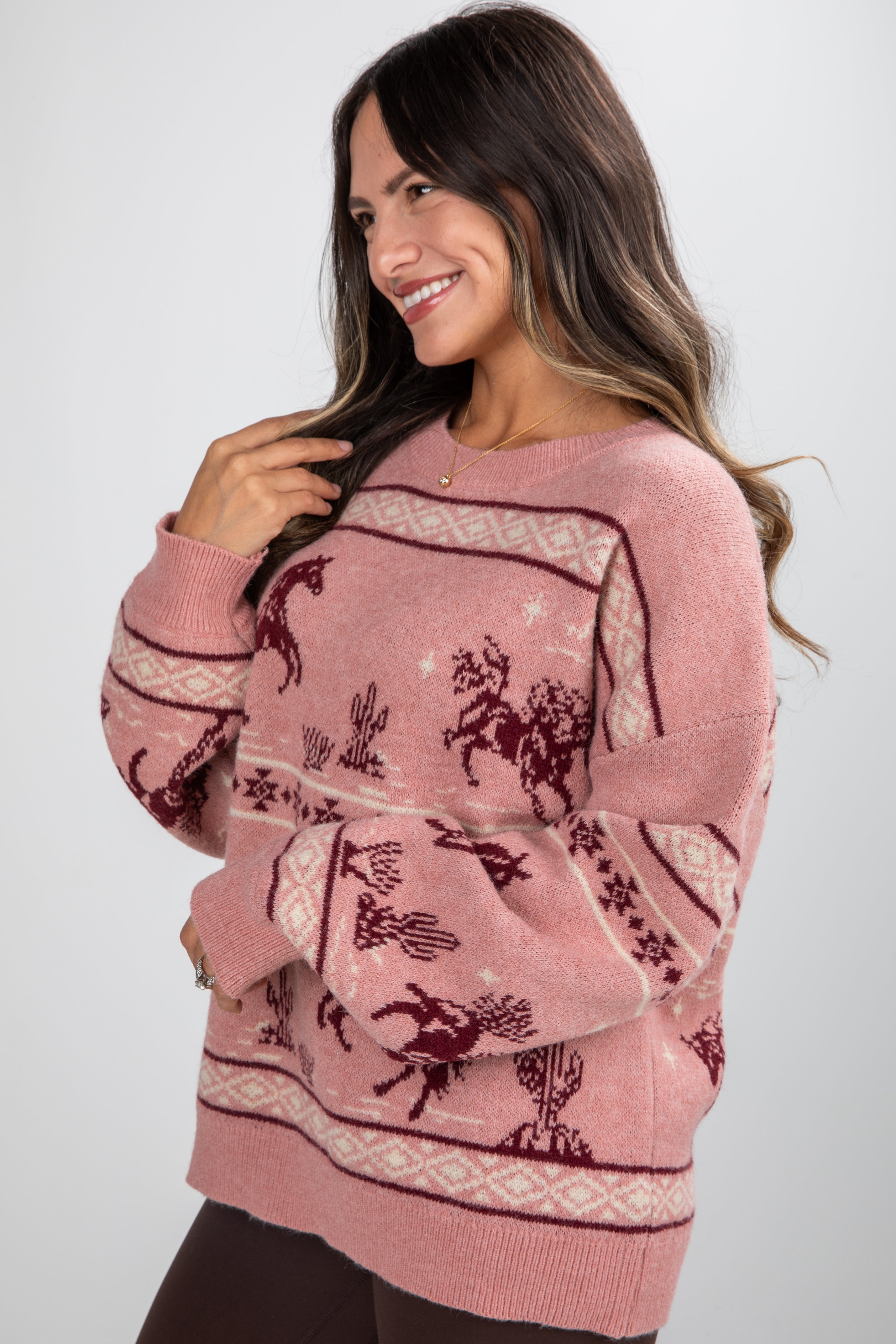 Woman wearing a pink sweater with a pattern on a white background