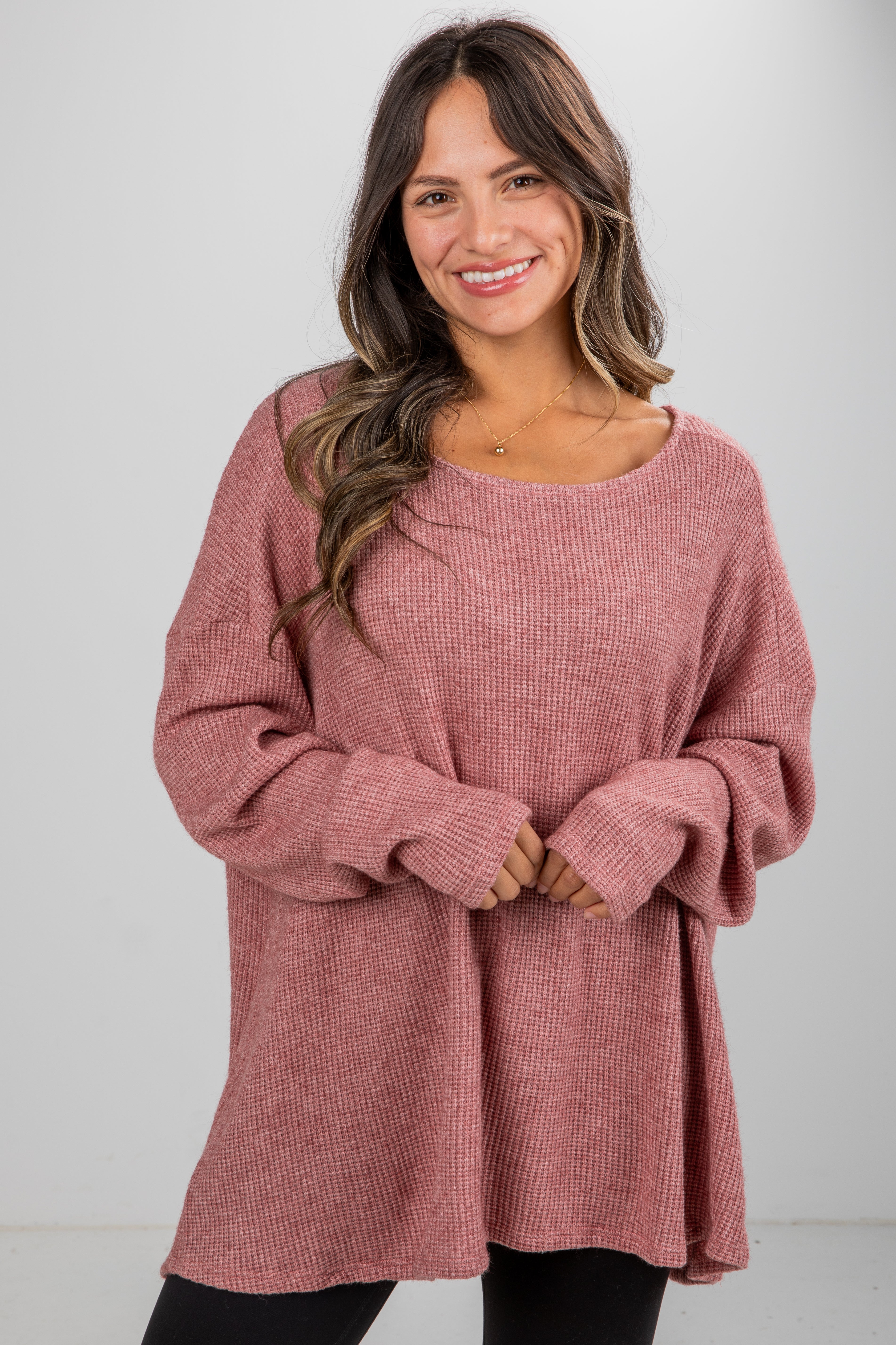 Woman wearing a pink sweater against a white background