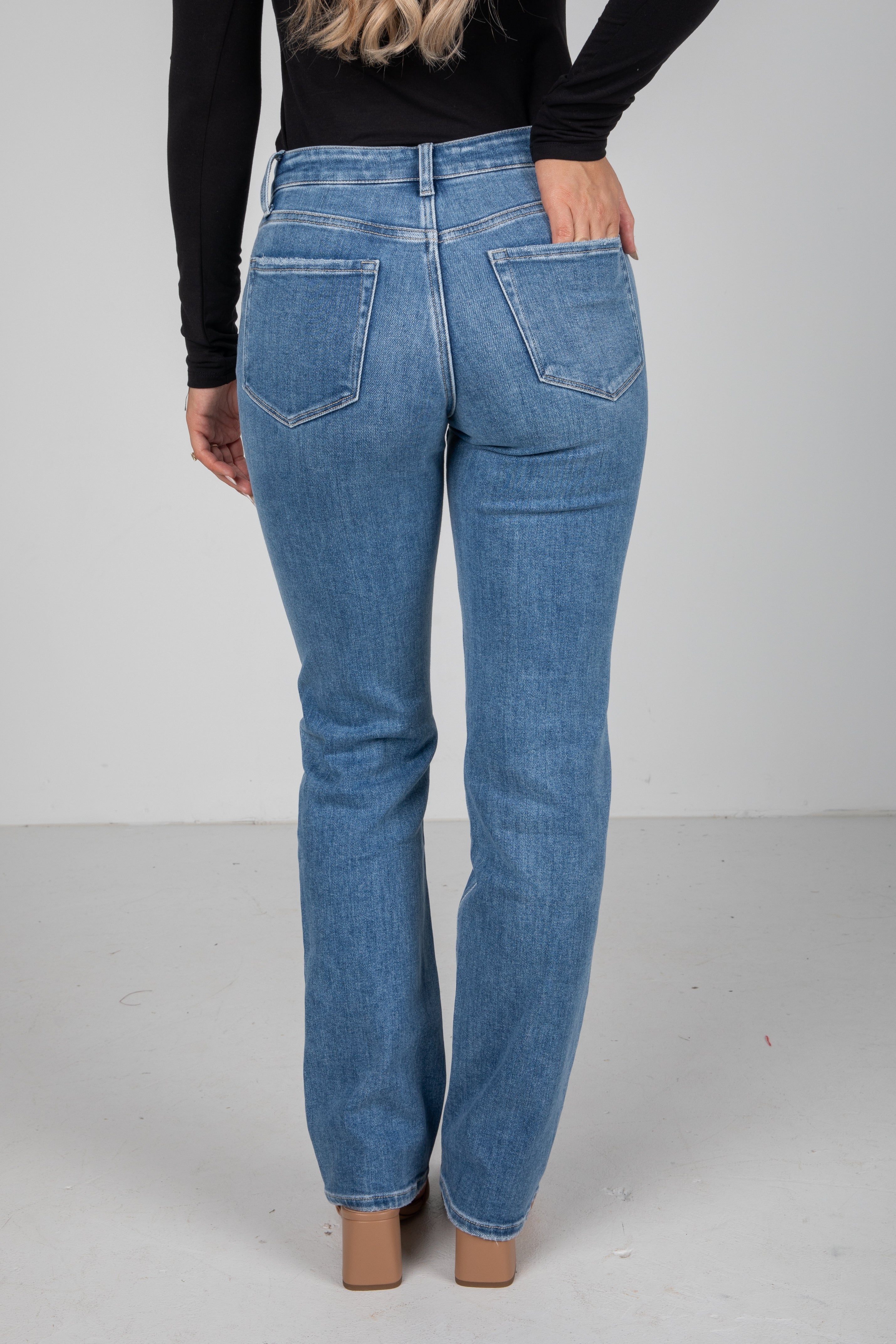 Person wearing blue jeans on a plain background
