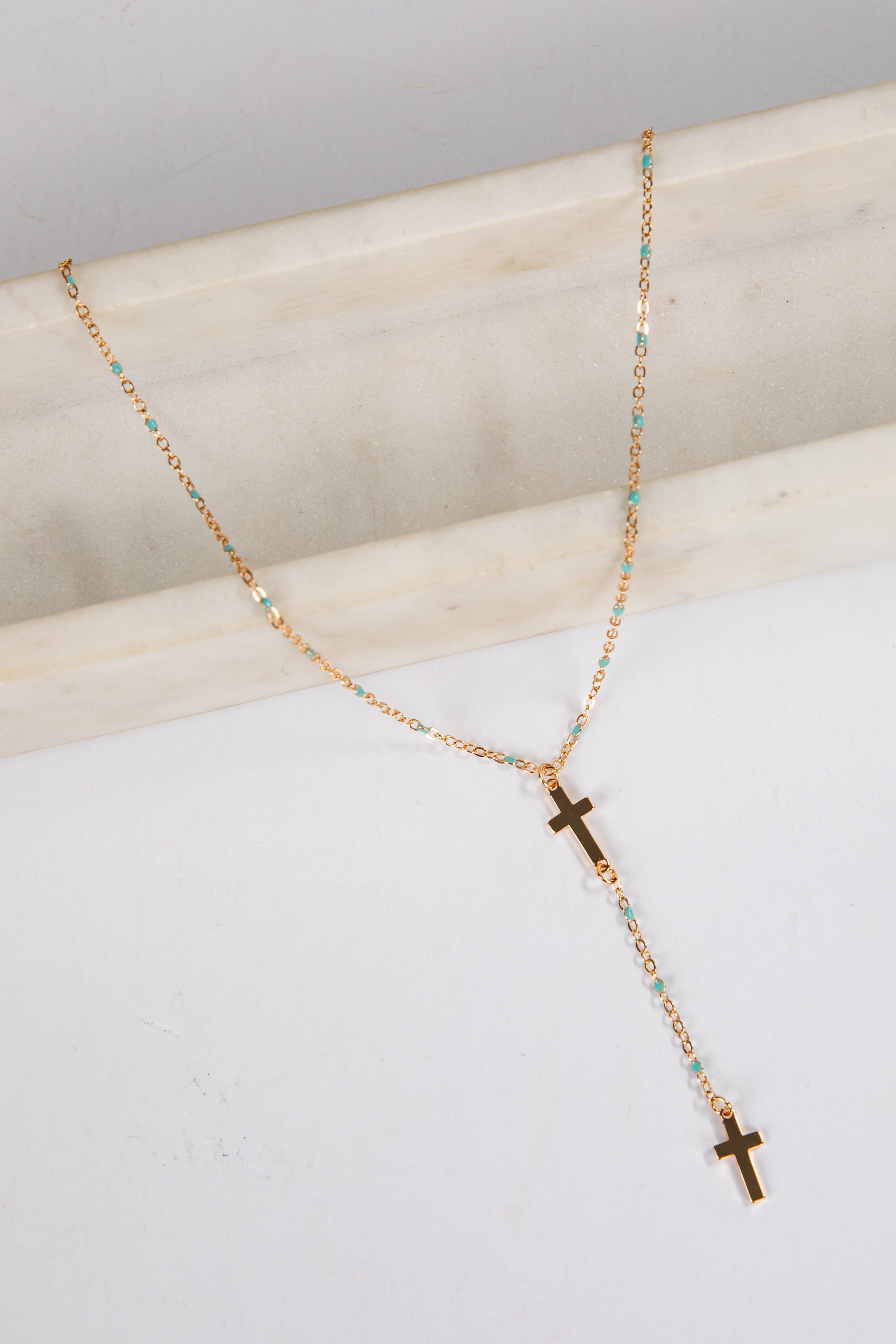 Necklace with cross pendants on a marble surface