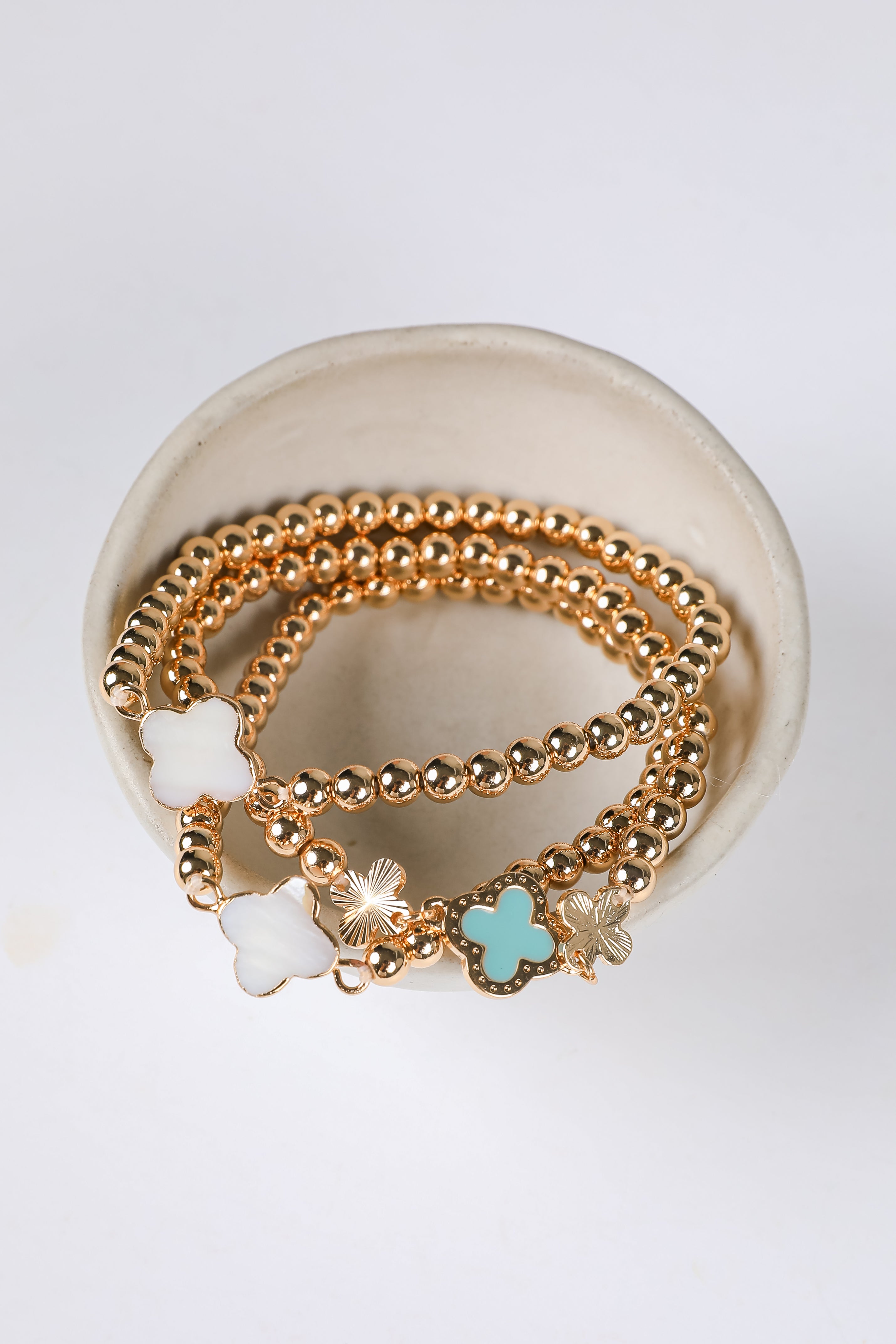 Gold bracelets with star-shaped charms on a white dish