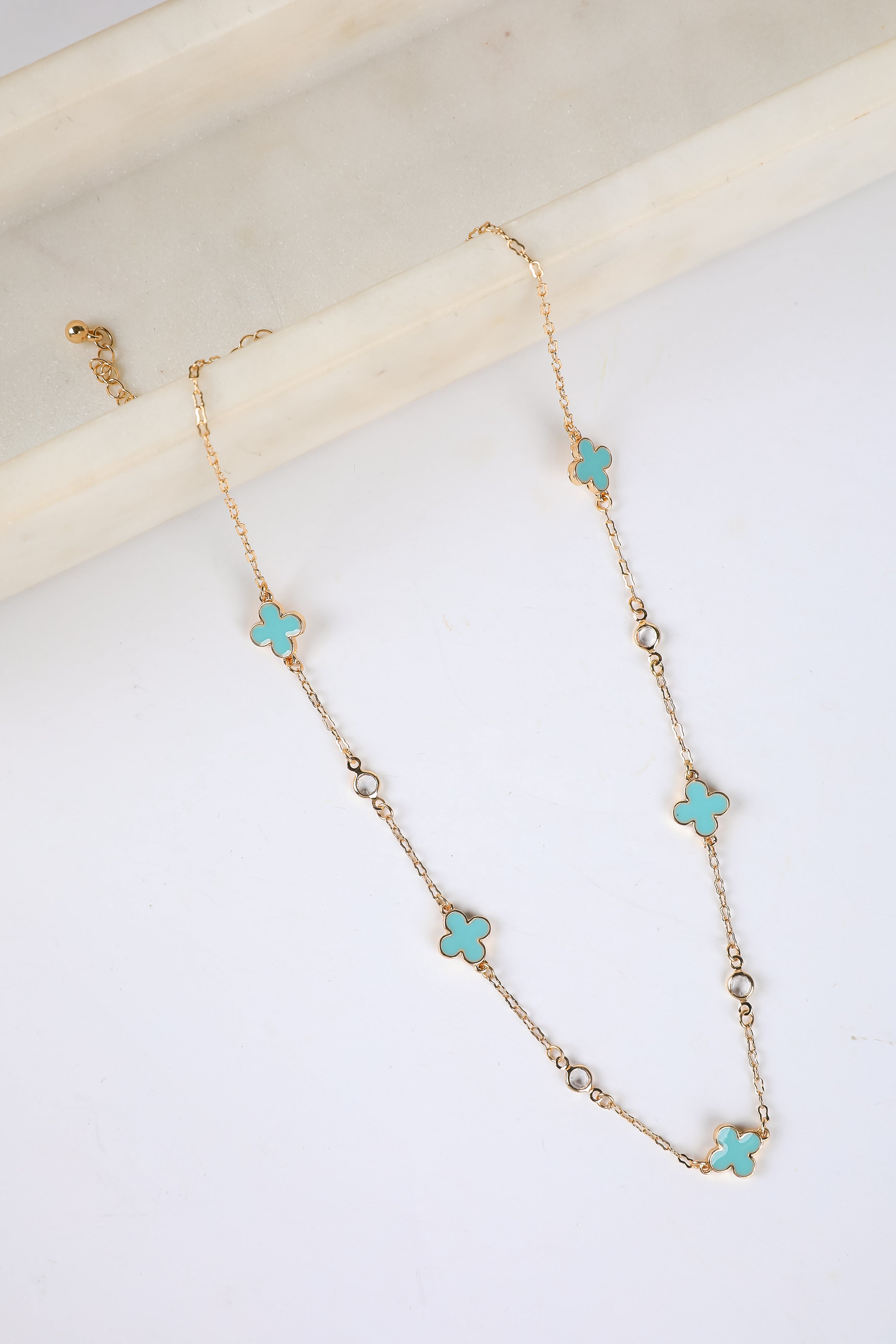 Necklace with turquoise clover pendants on a white surface