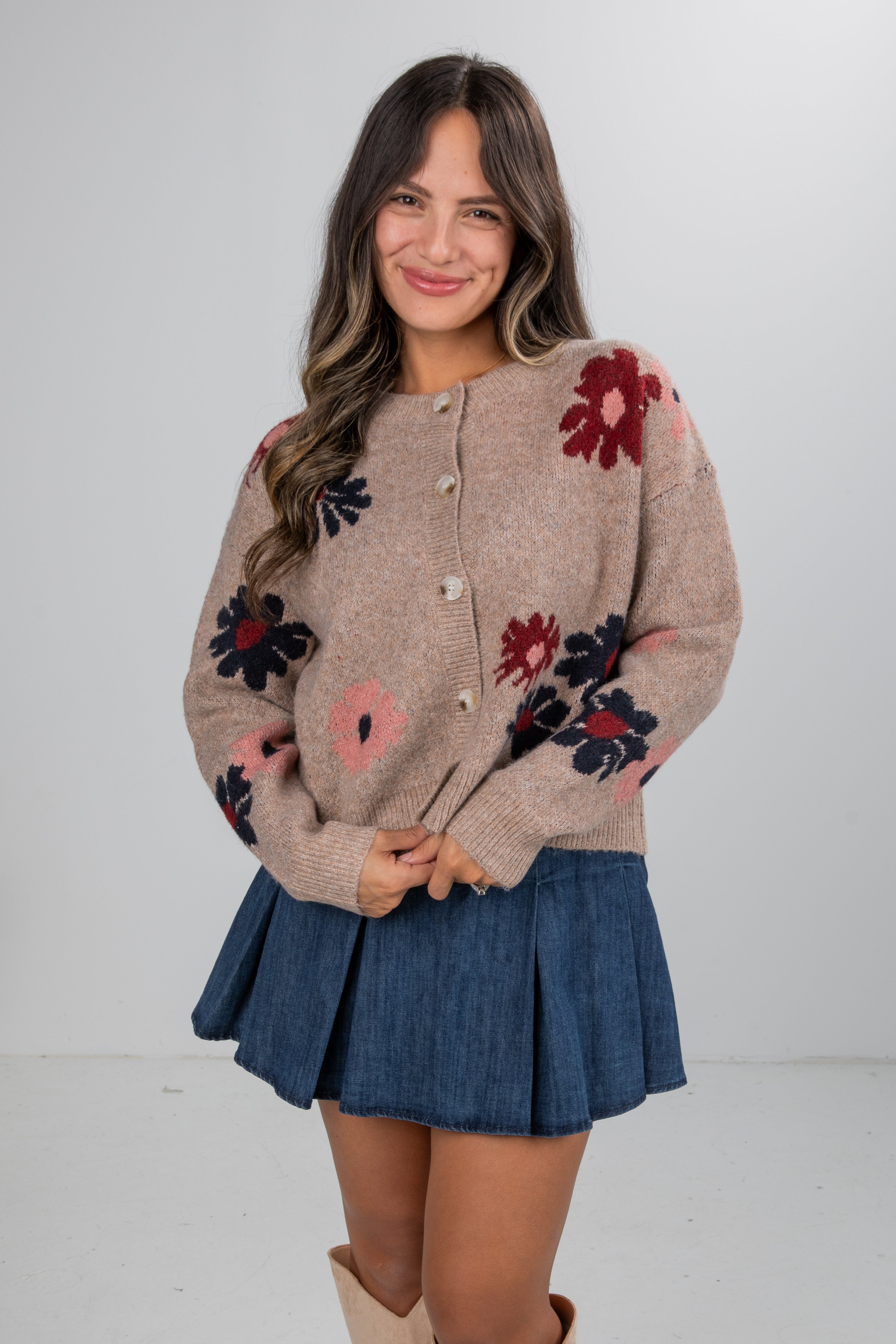 Woman wearing a floral cardigan and denim skirt on a white background