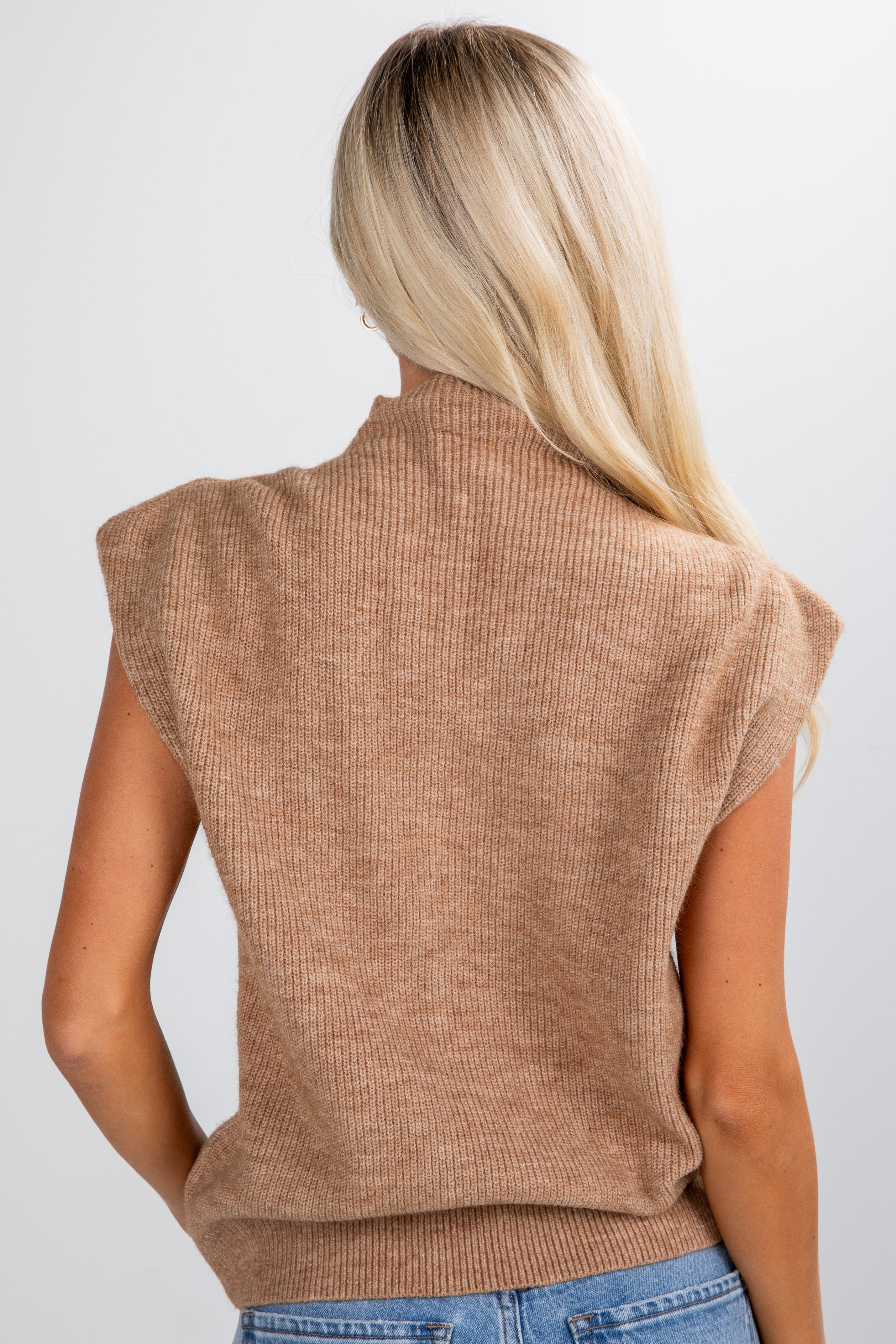 Woman wearing a brown sleeveless sweater vest on a white background