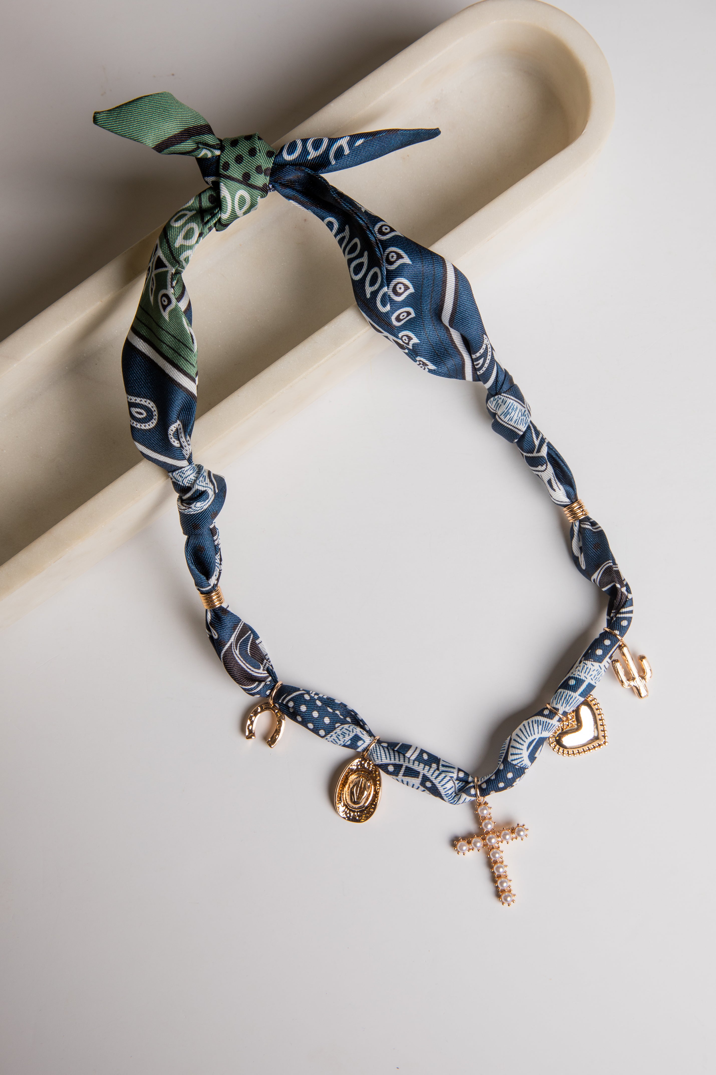 Necklace with blue bandana pattern and gold charms on a white surface