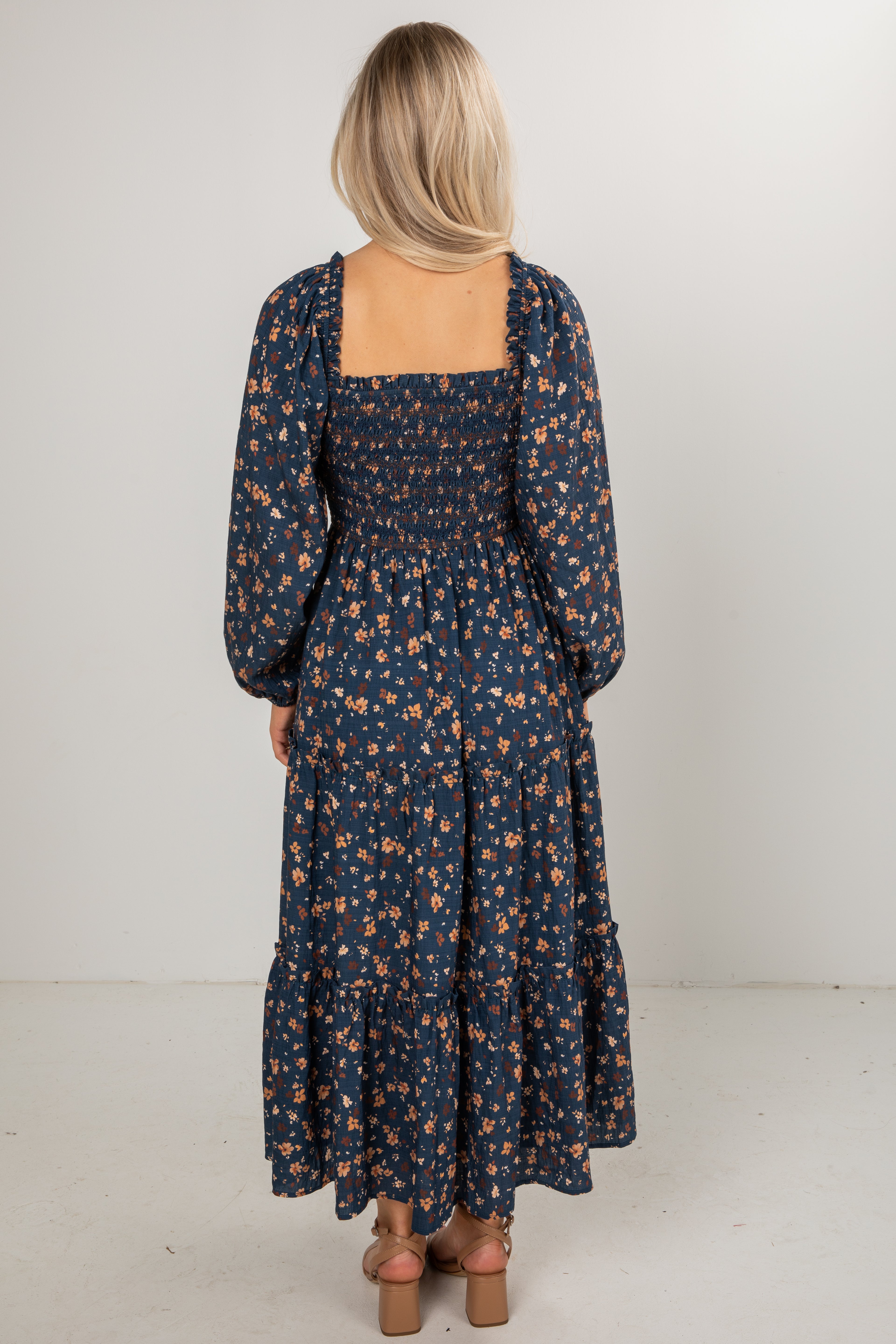 Woman wearing a long floral dress with a plain background