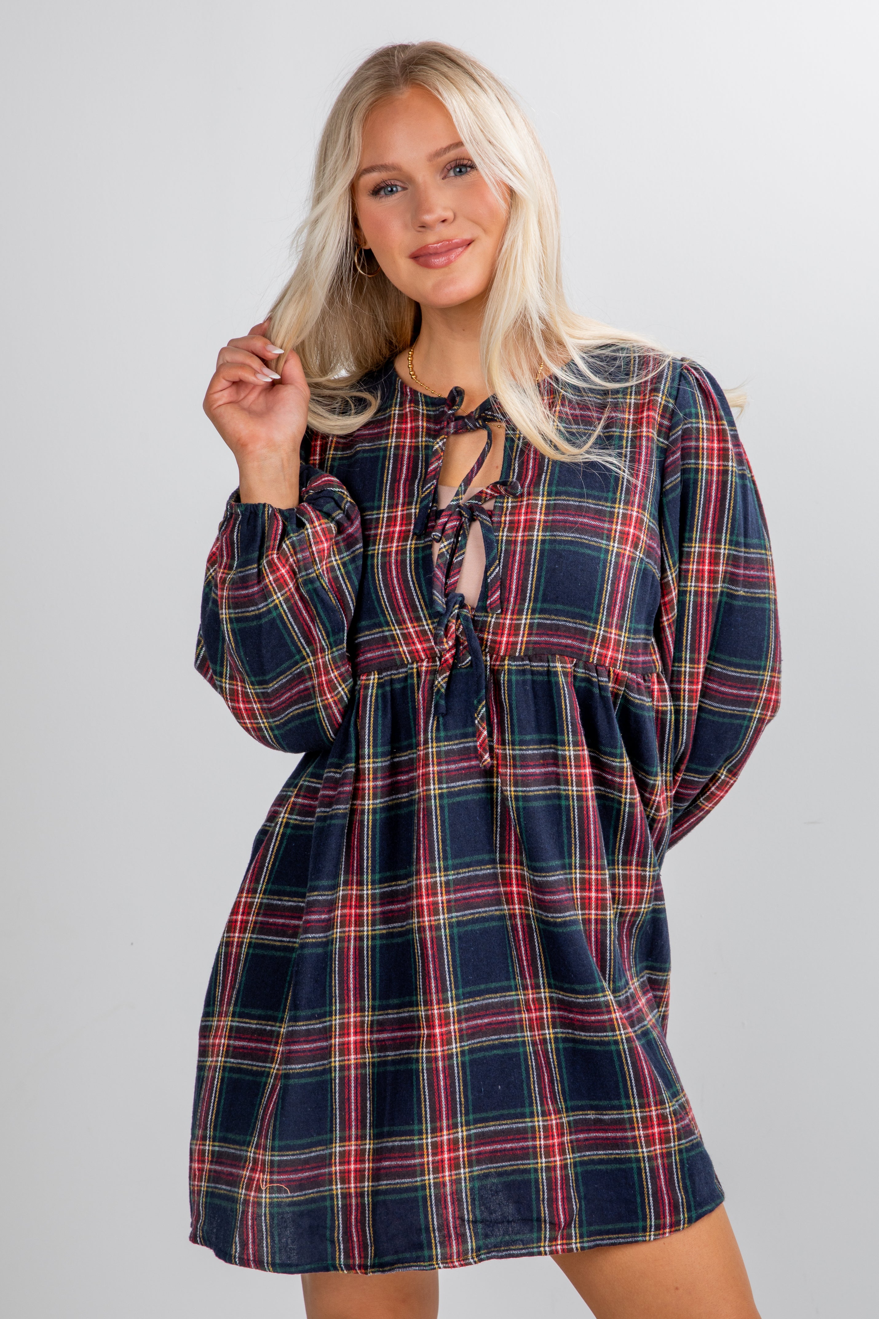 Woman wearing a plaid dress with long sleeves on a plain background