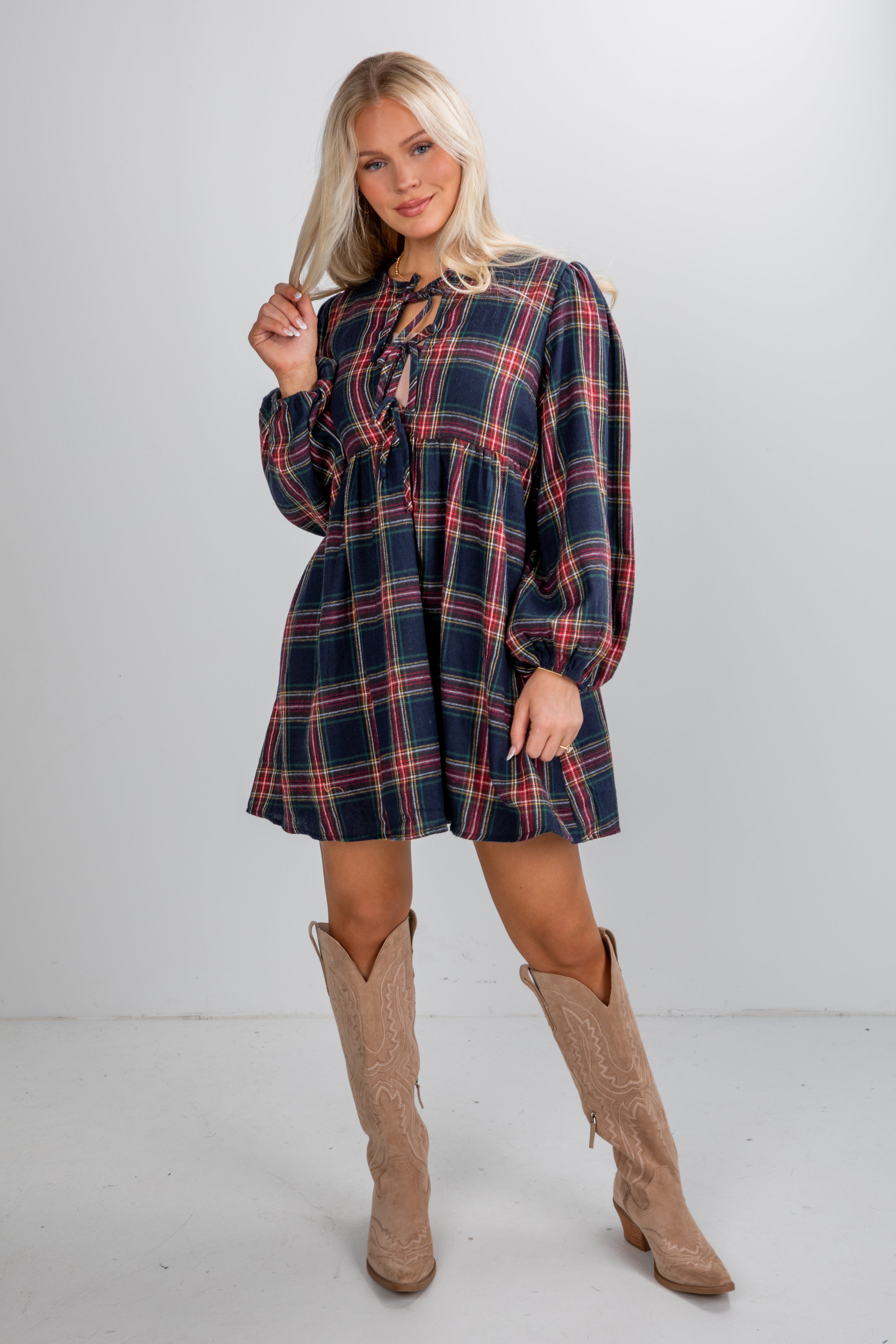 Woman wearing a plaid dress and brown boots on a white background