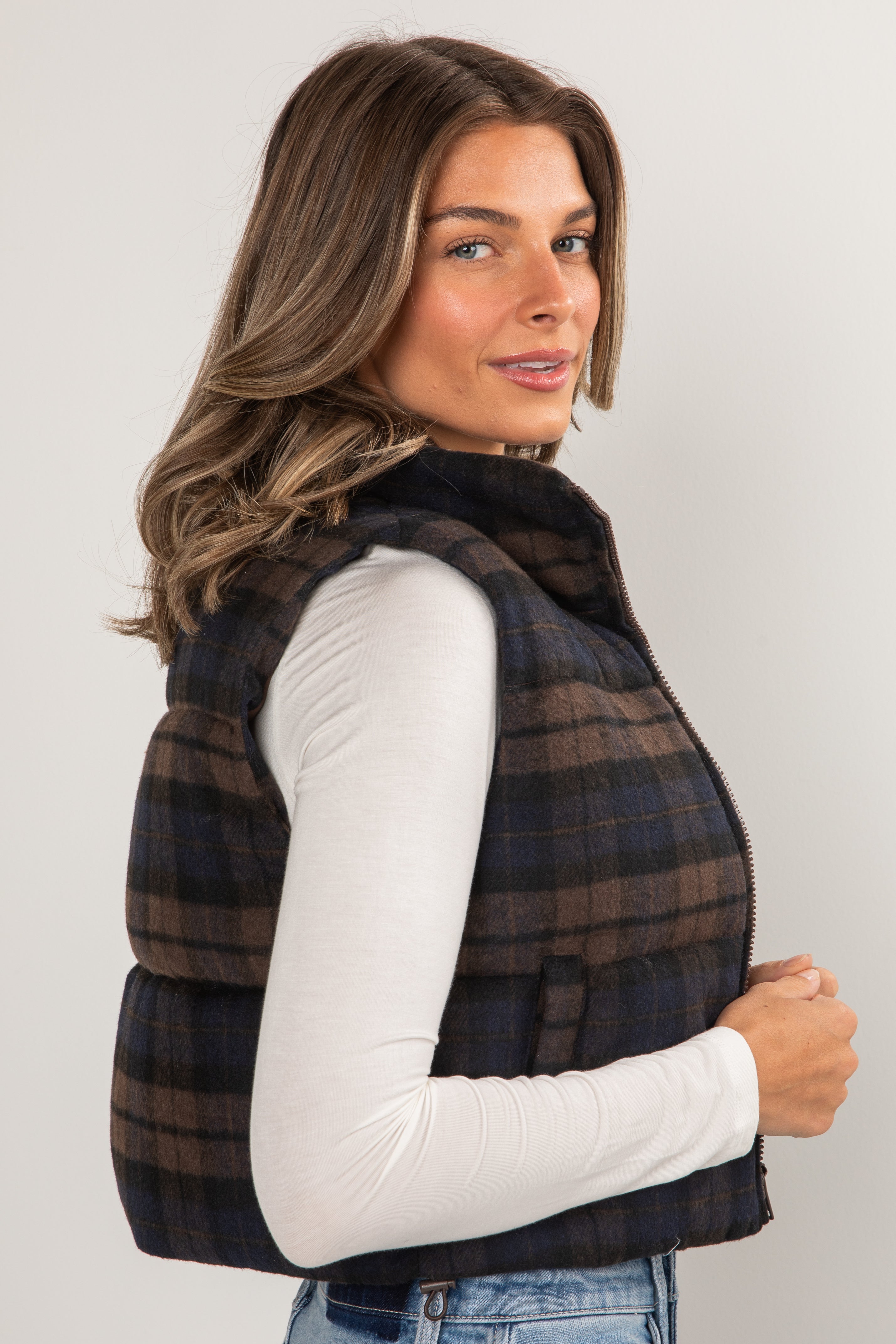 Woman wearing a plaid vest over a white shirt on a plain background