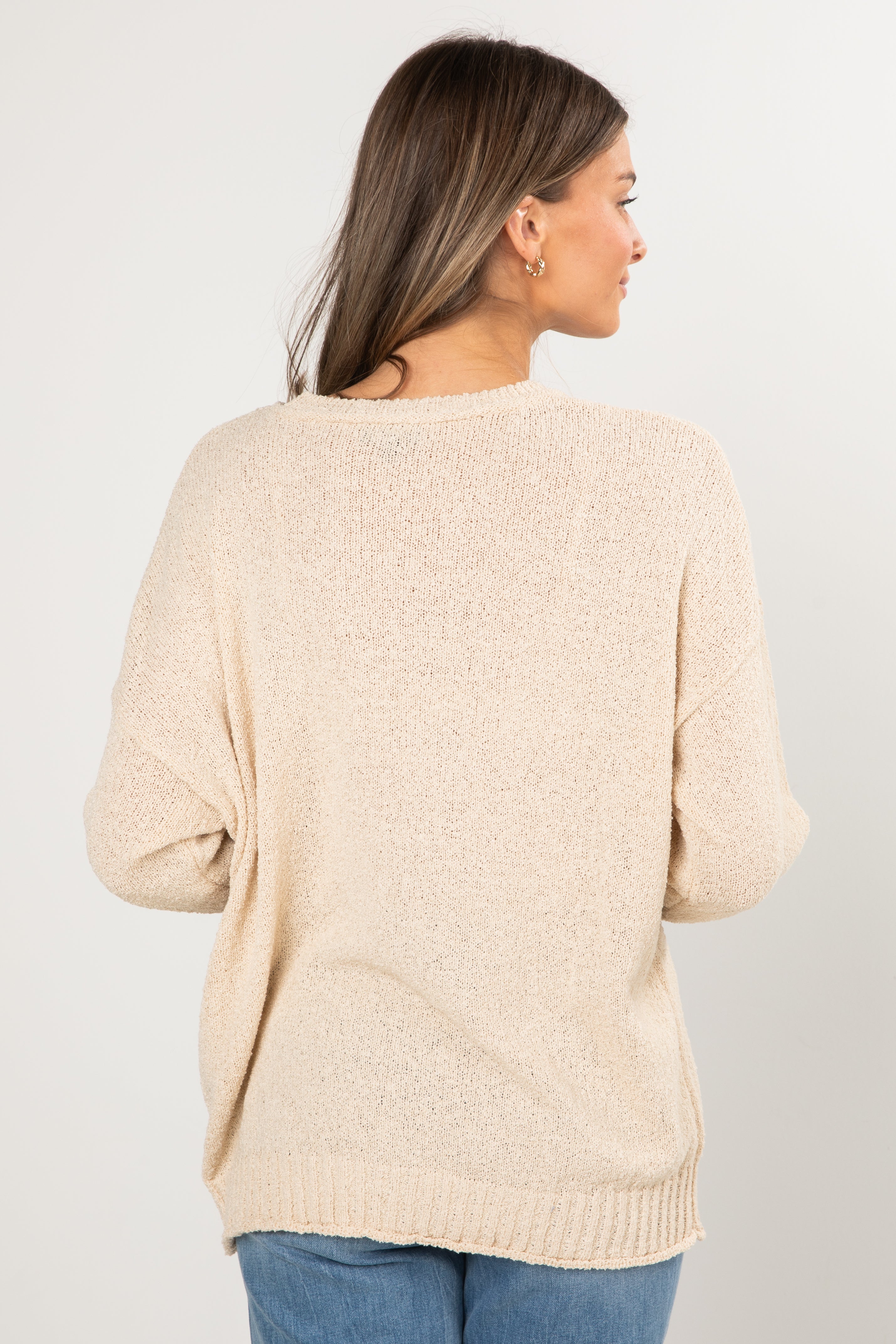 Woman wearing a beige sweater on a plain background