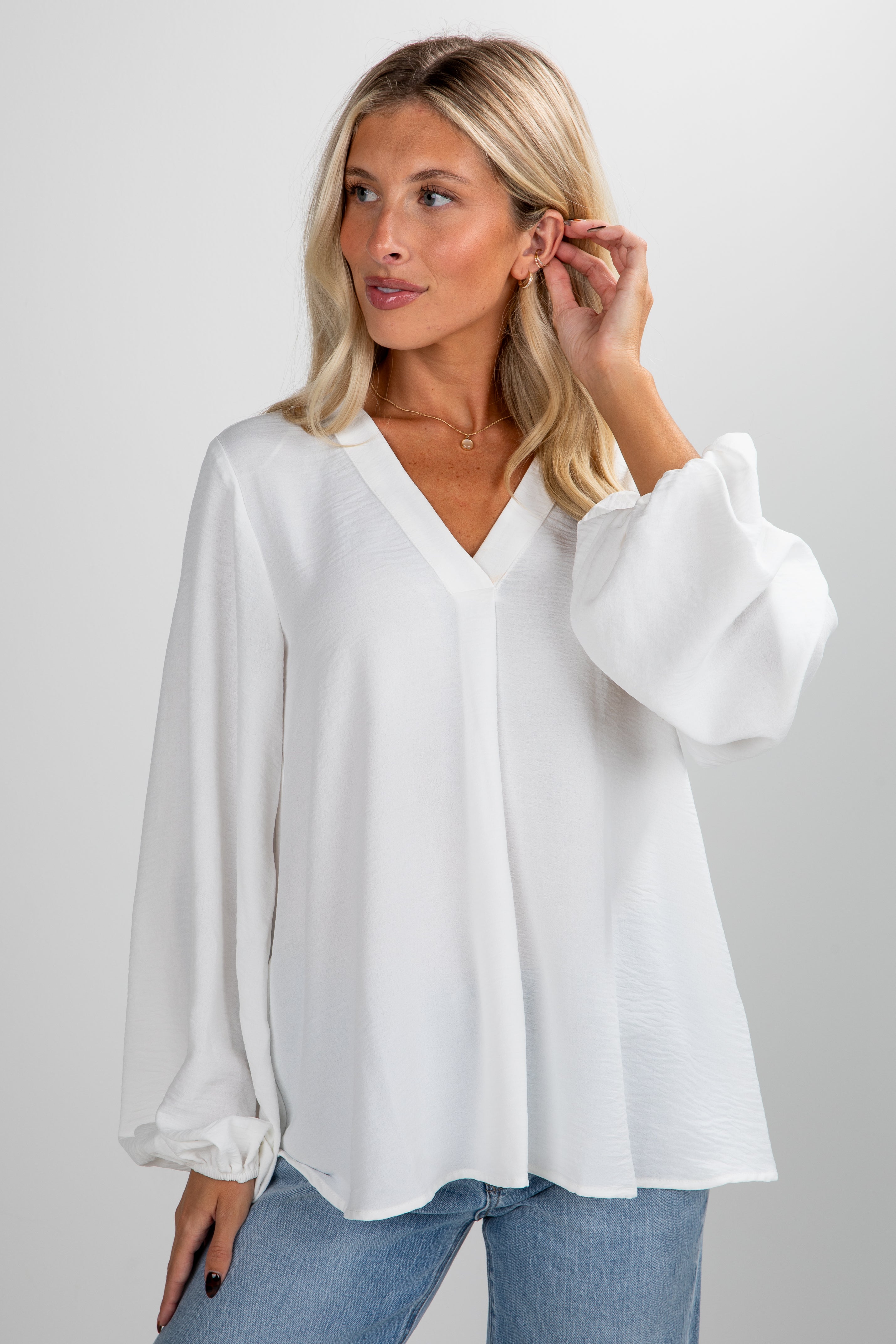 Woman wearing a white blouse and blue jeans on a plain background